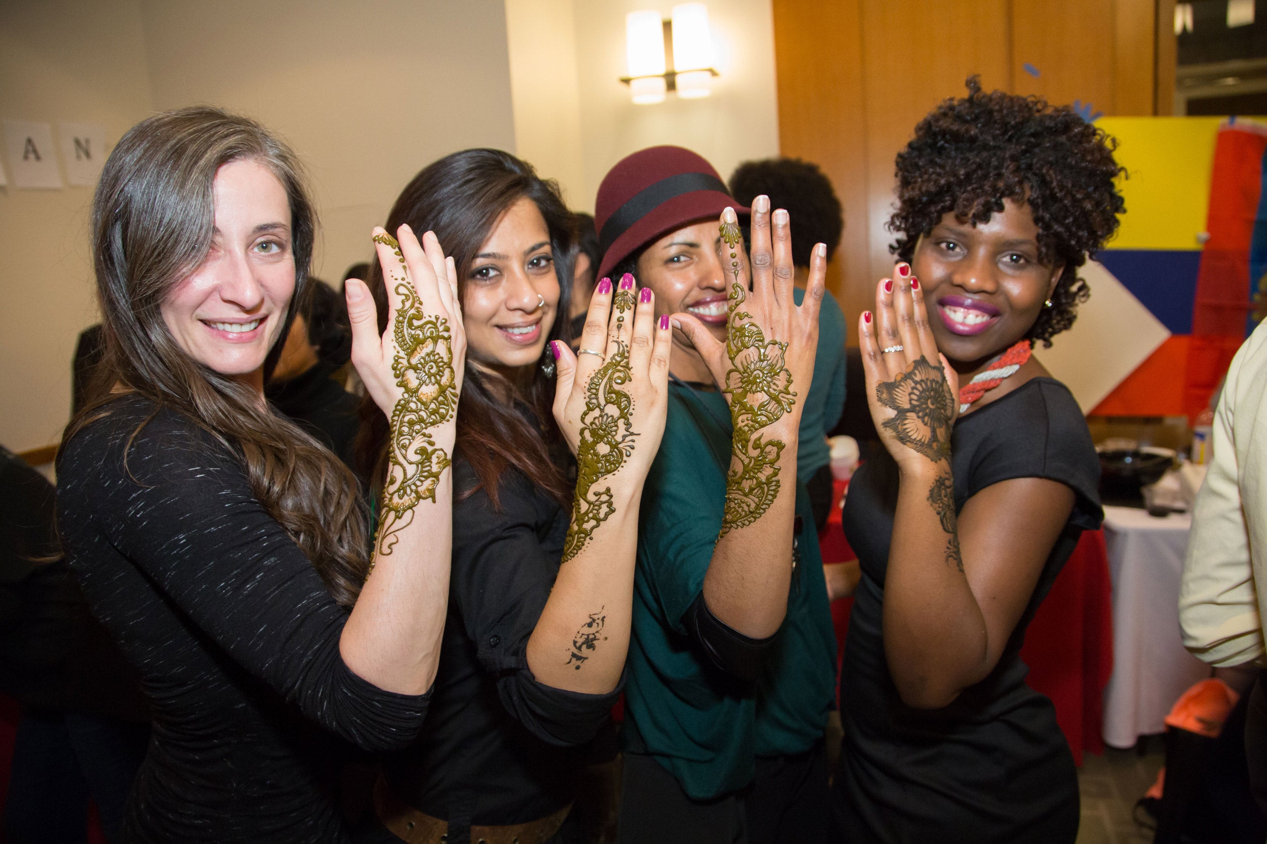 Four women show off the henna on their hands and arms