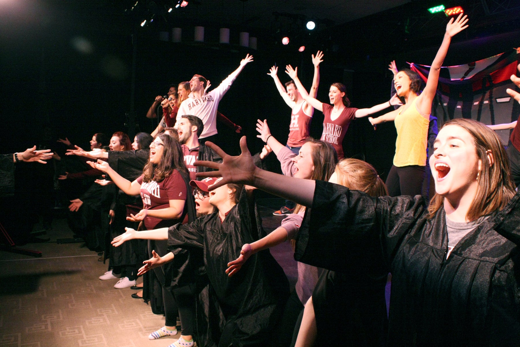 Students on stage singing in black gowns