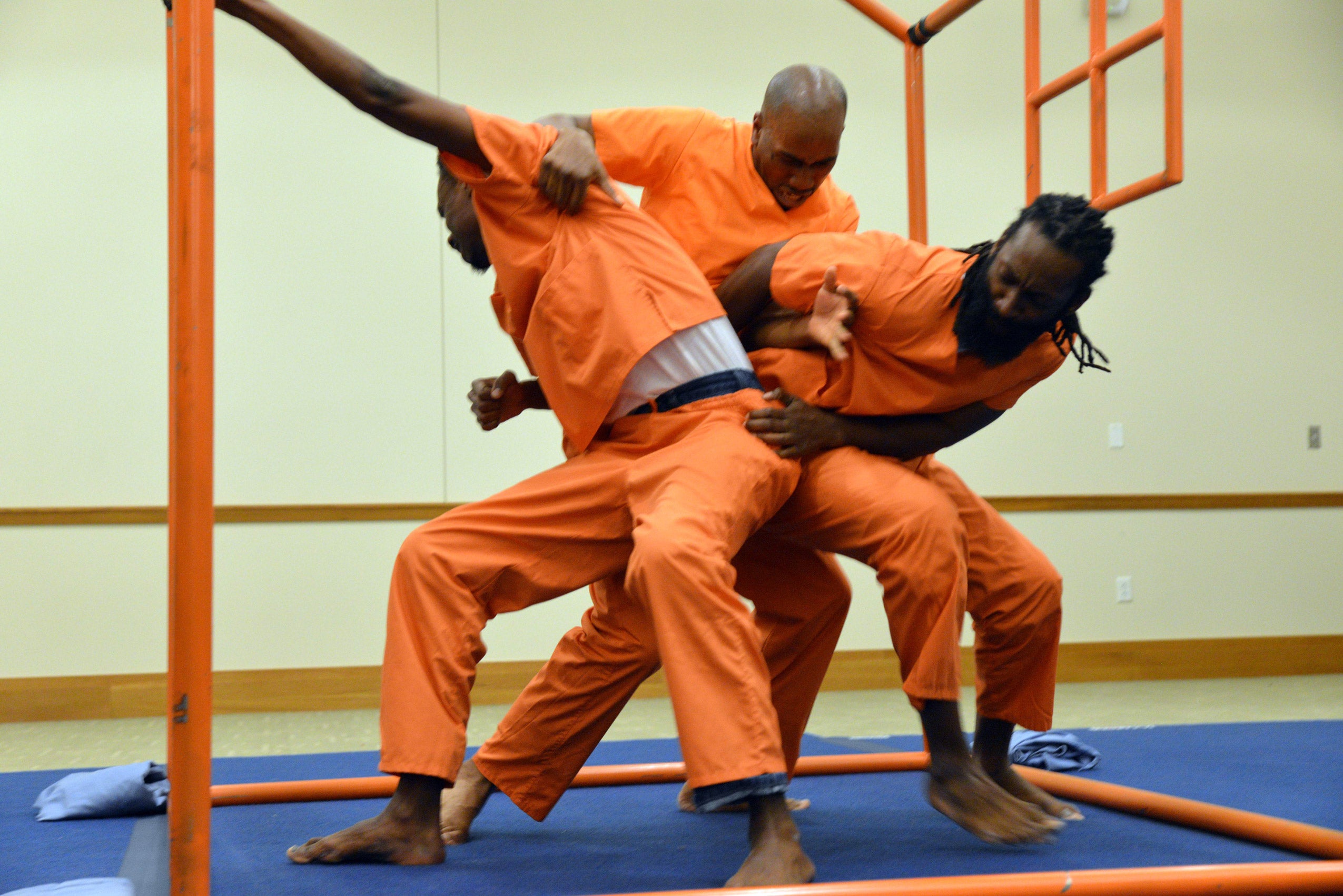Three men in orange costumes performing