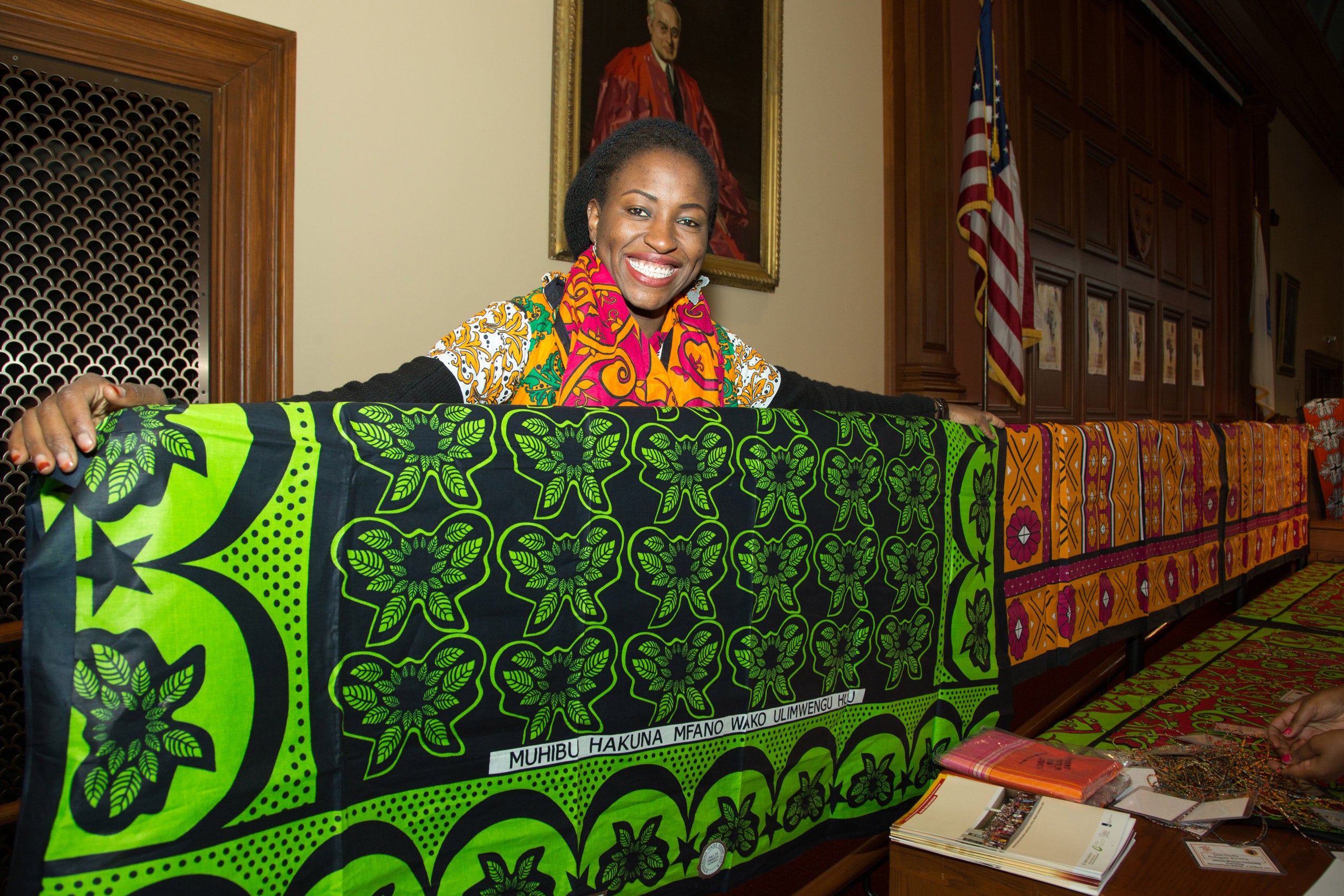 A woman smiling and holding up a tapestry