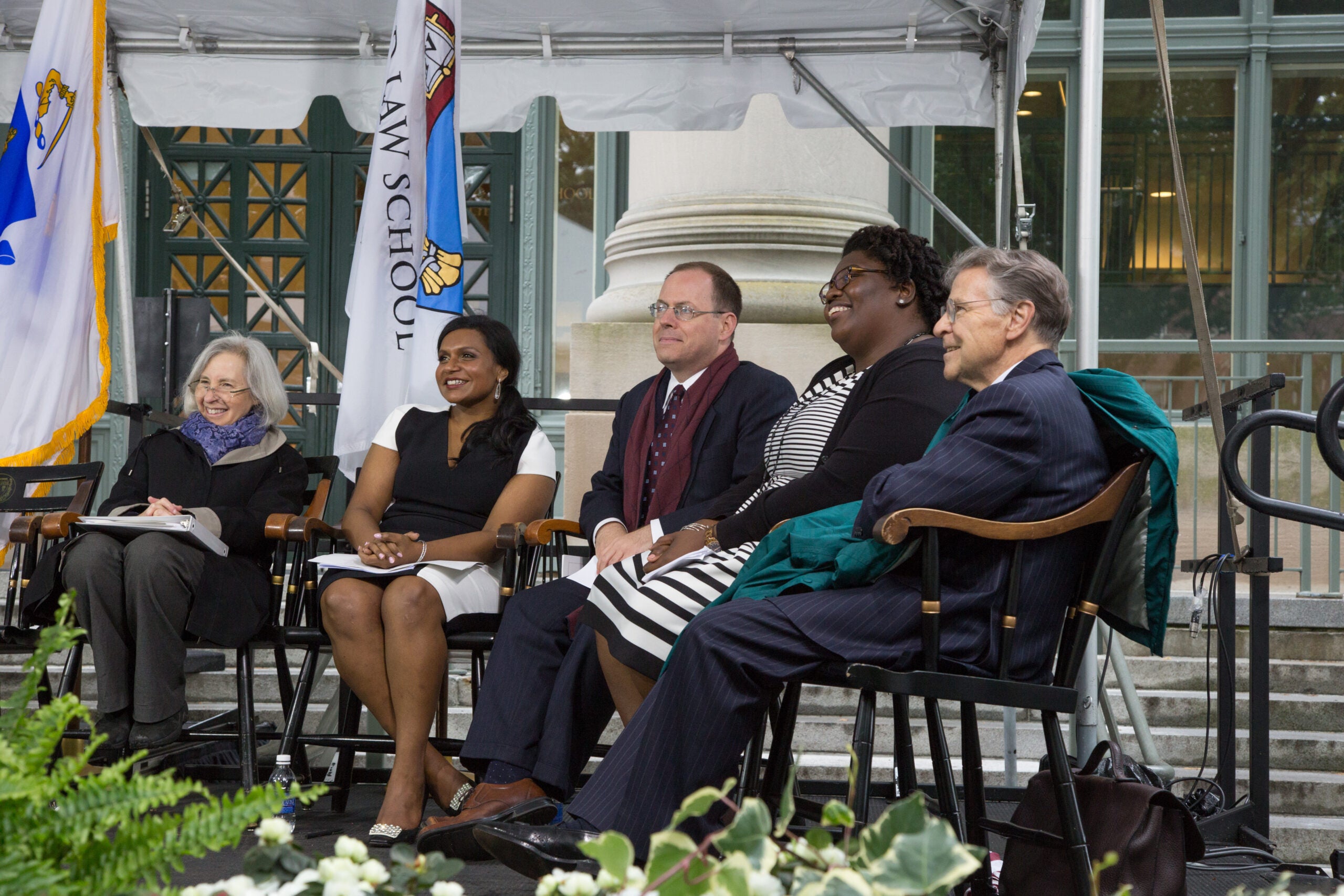 A group of men and women seated on stage and smiling
