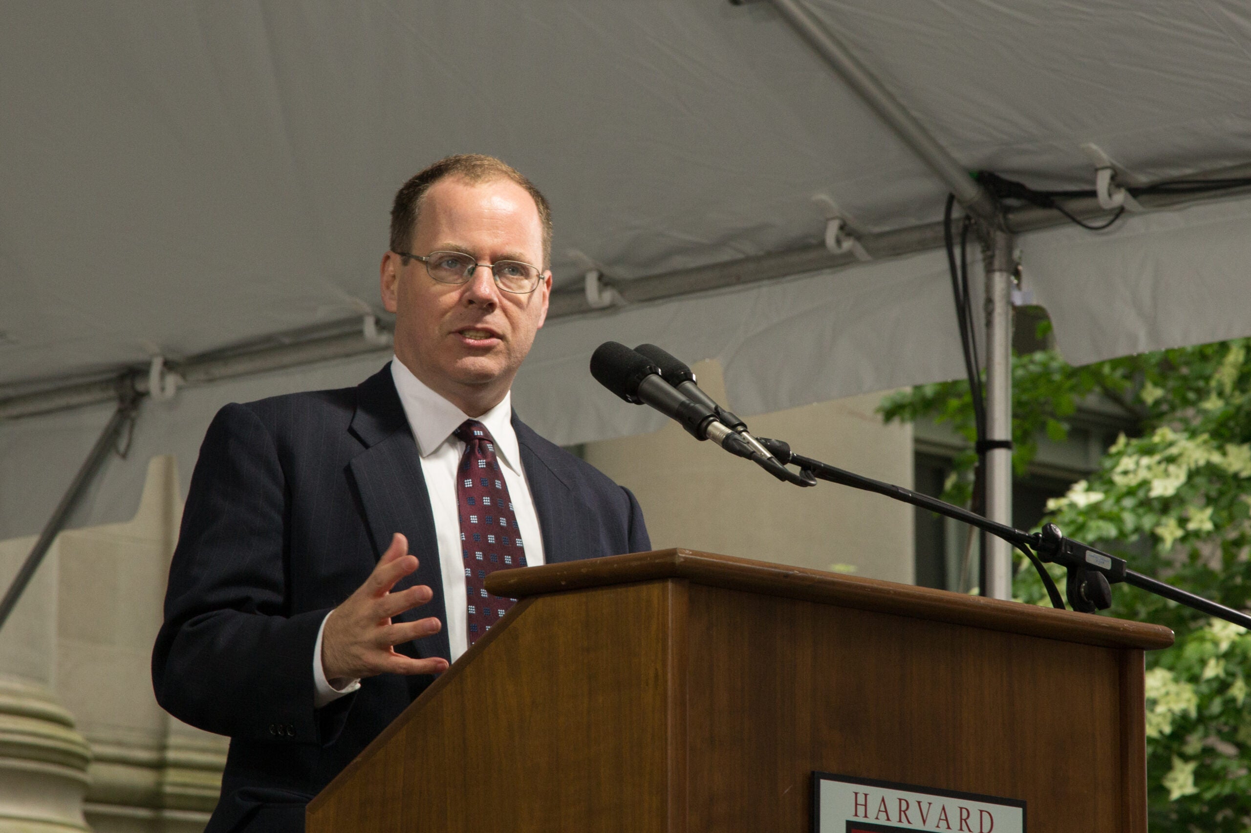 A man speaking into a microphone at a posium