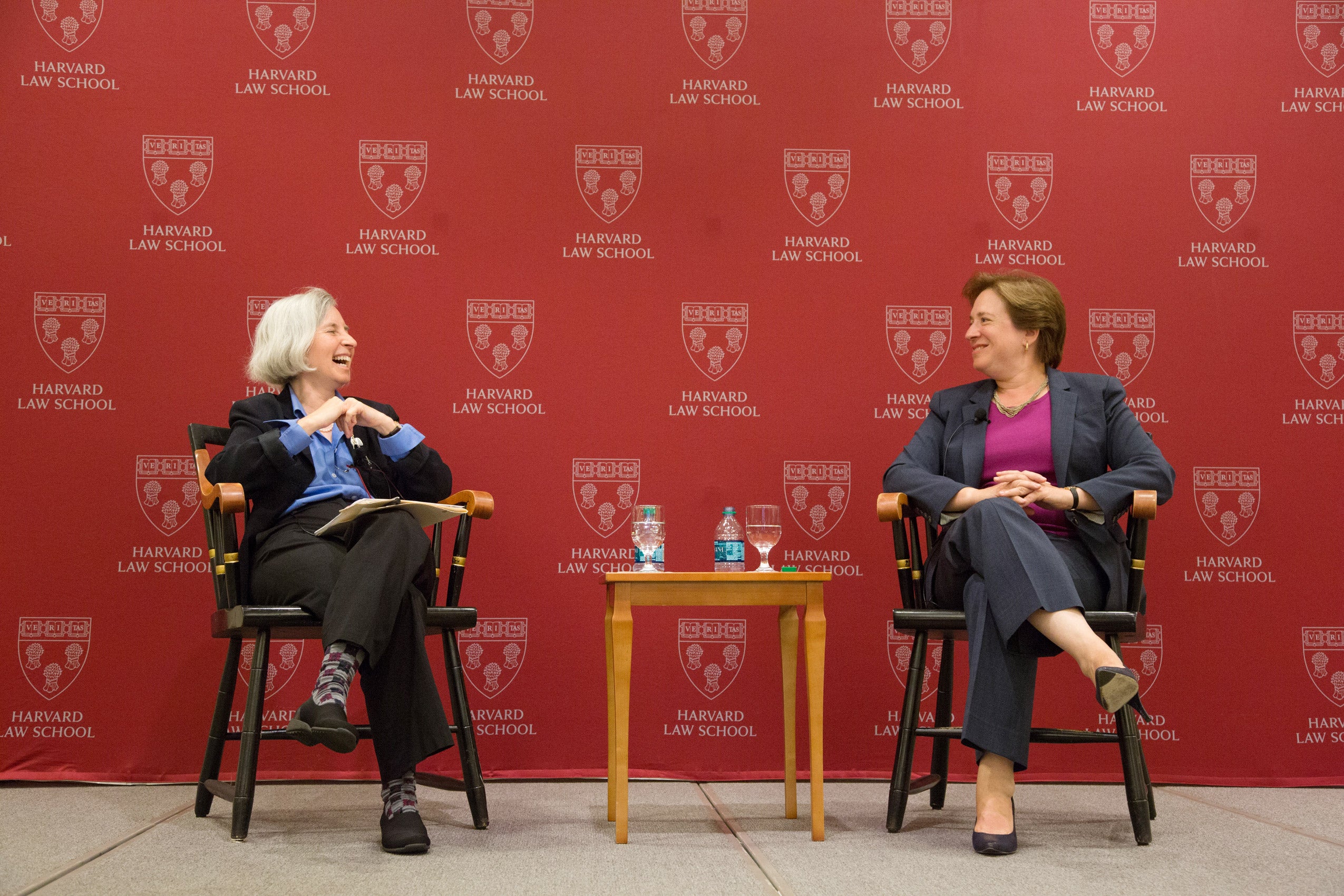 Two women sitting on stage, laughing and talking