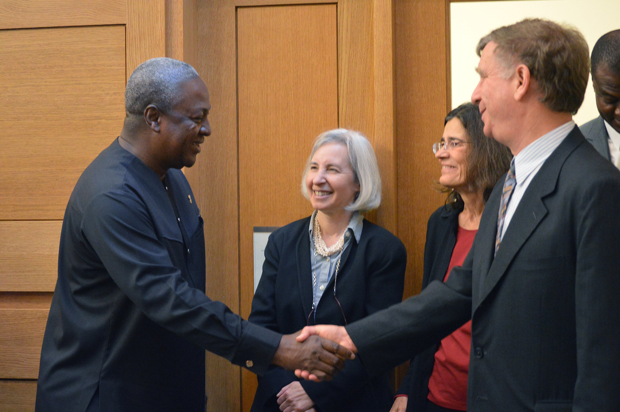 Two men shaking hands as two women look on, smiling