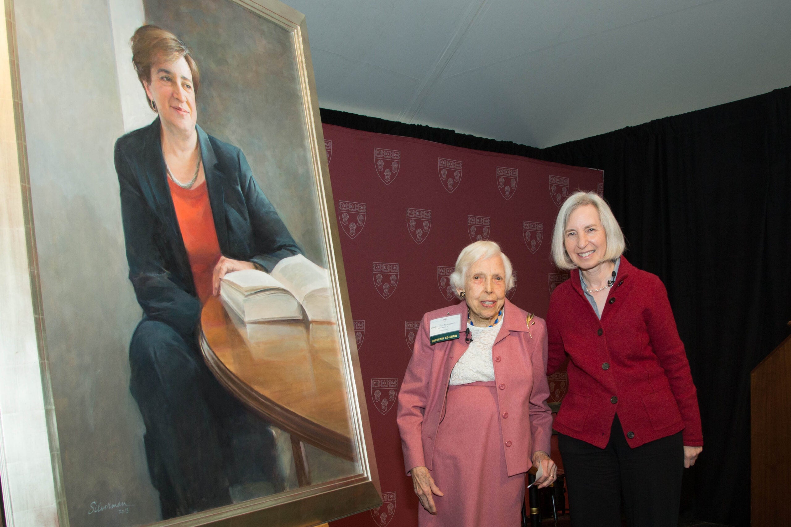 Two people standing together in front of Elena Kagan painting