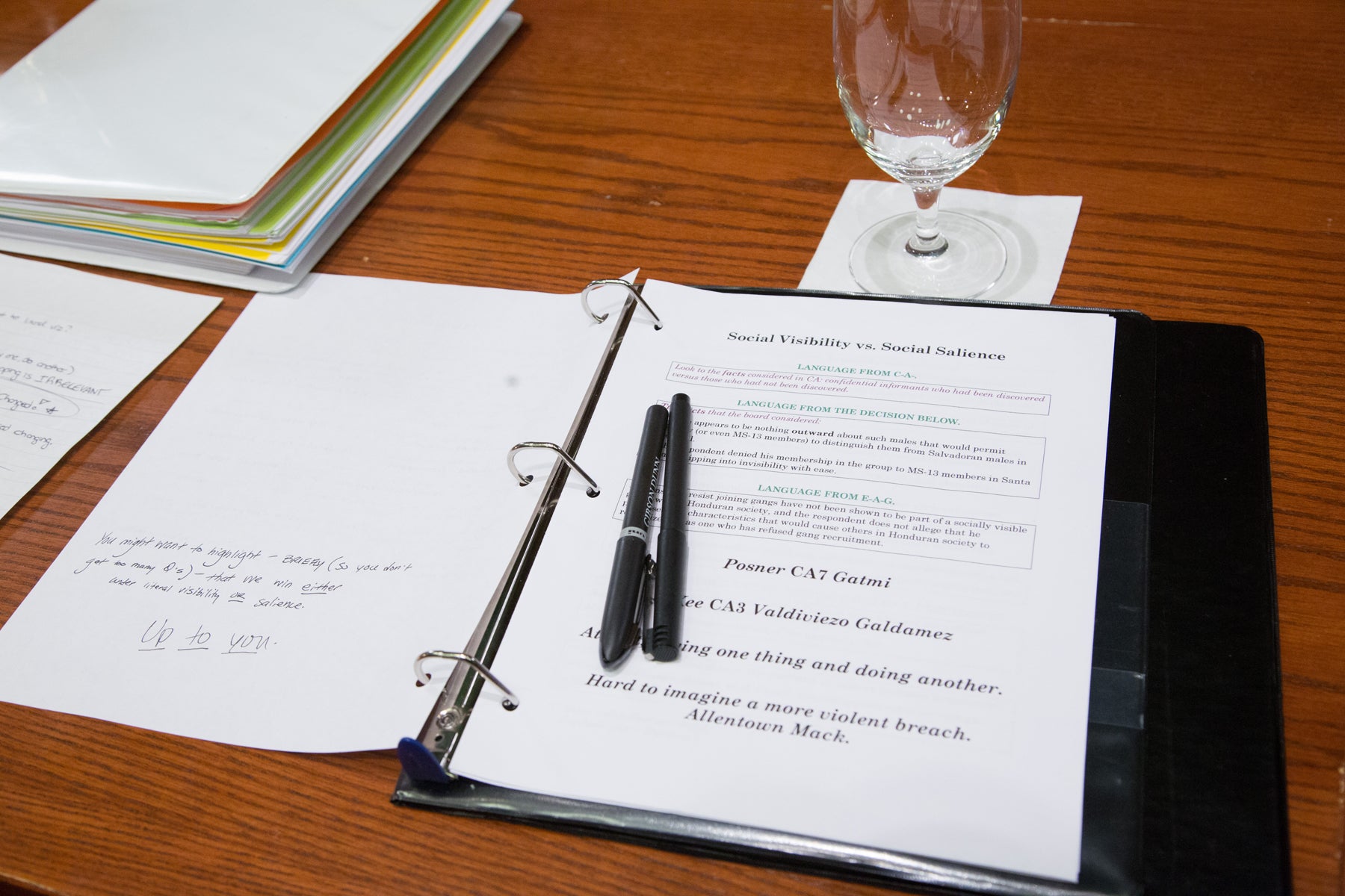 A three-ring binder with papers and pens on top