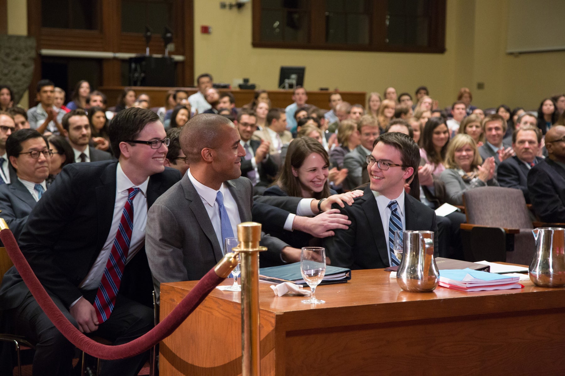 group of people congratulating someone with their hands on his shoulder