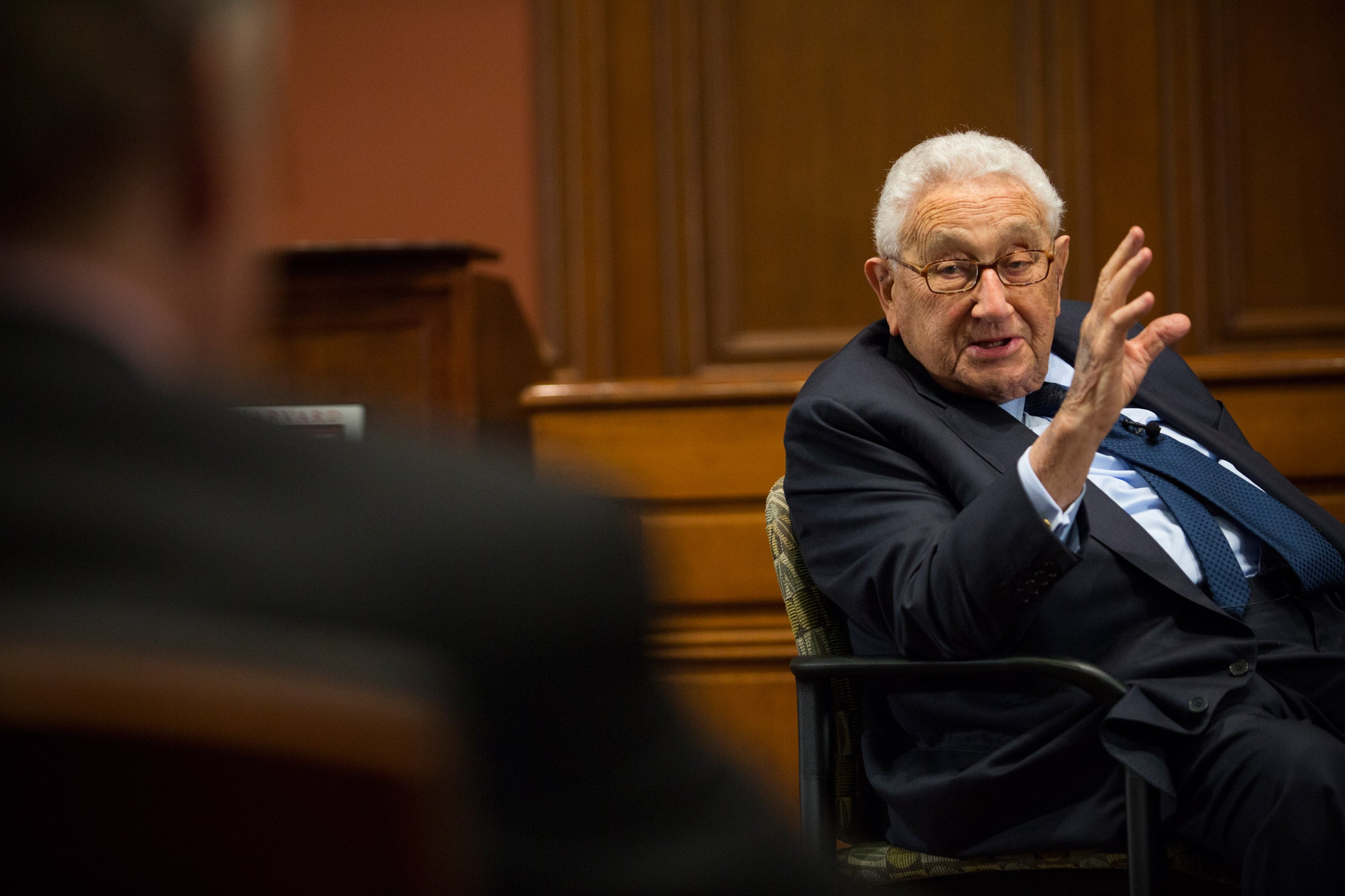 A man seated on stage and speaking