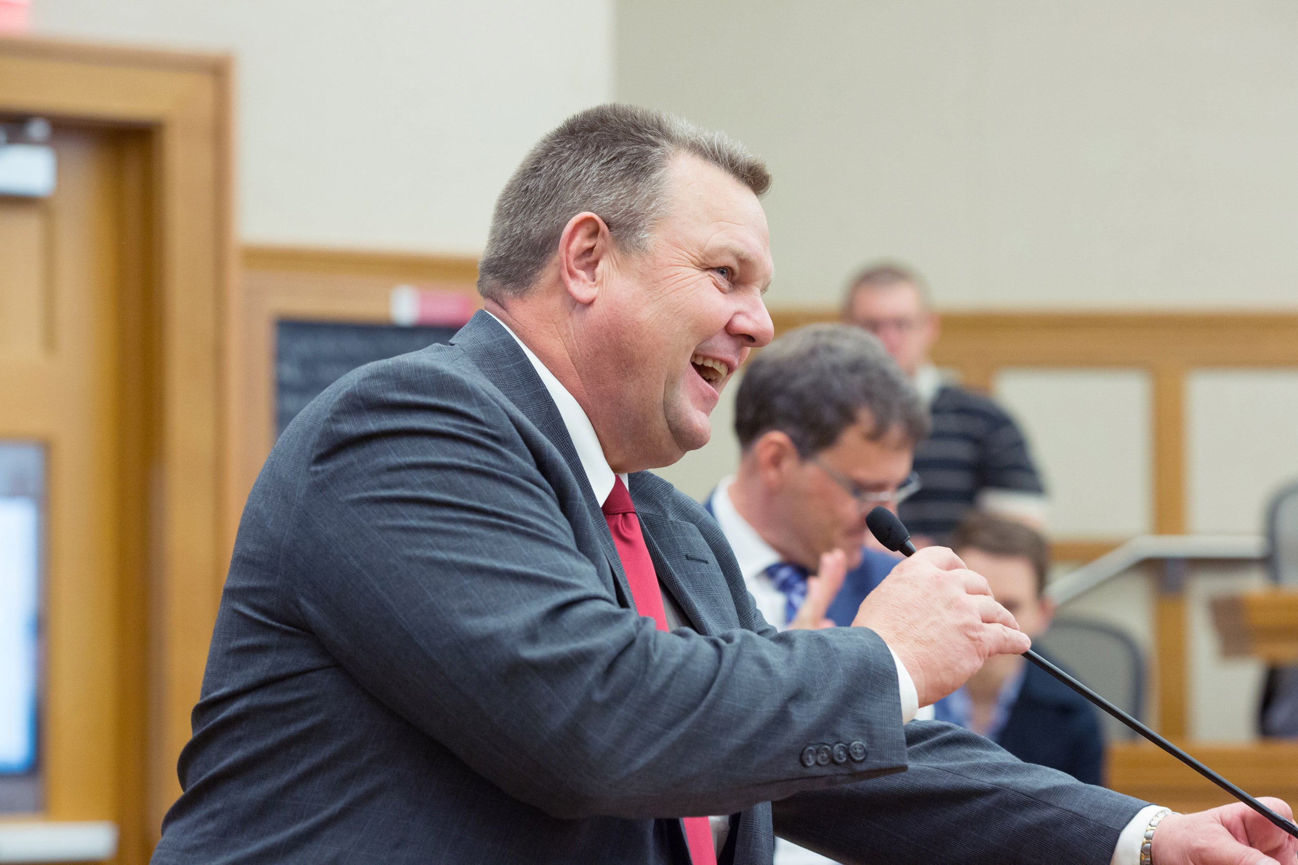 A man smiling and speaking into a microphone