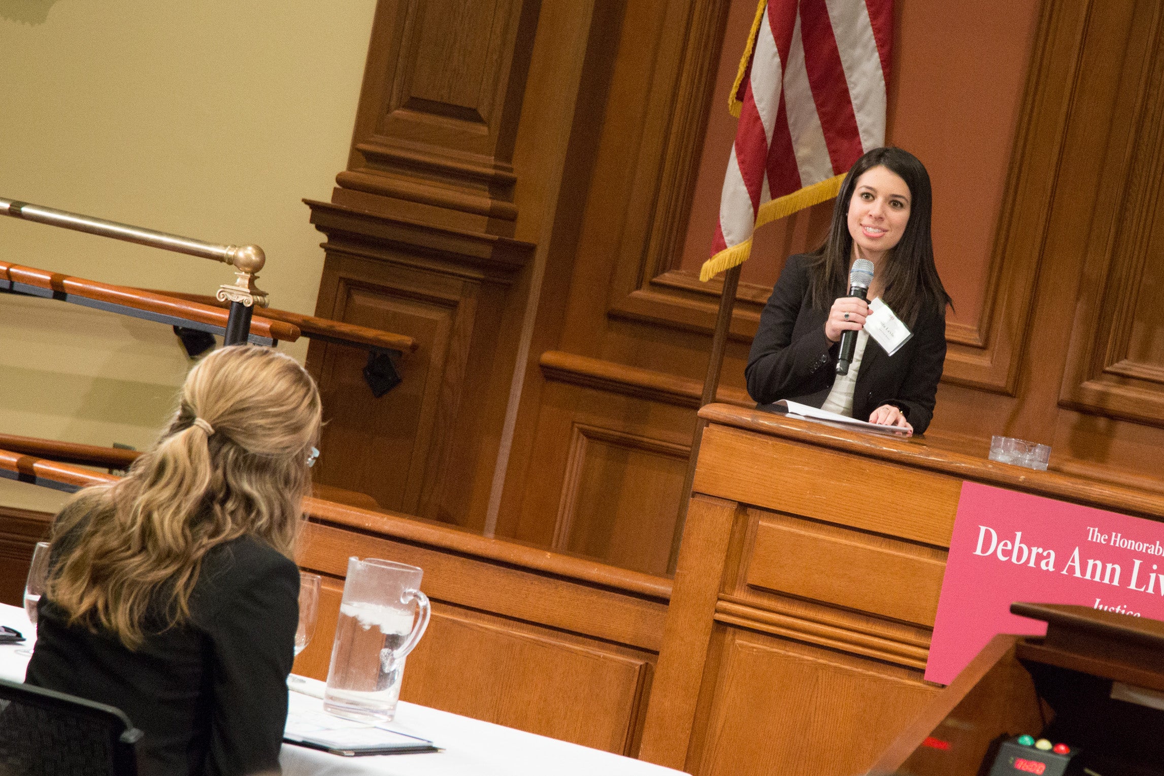 A woman holding a microphone behind the desk