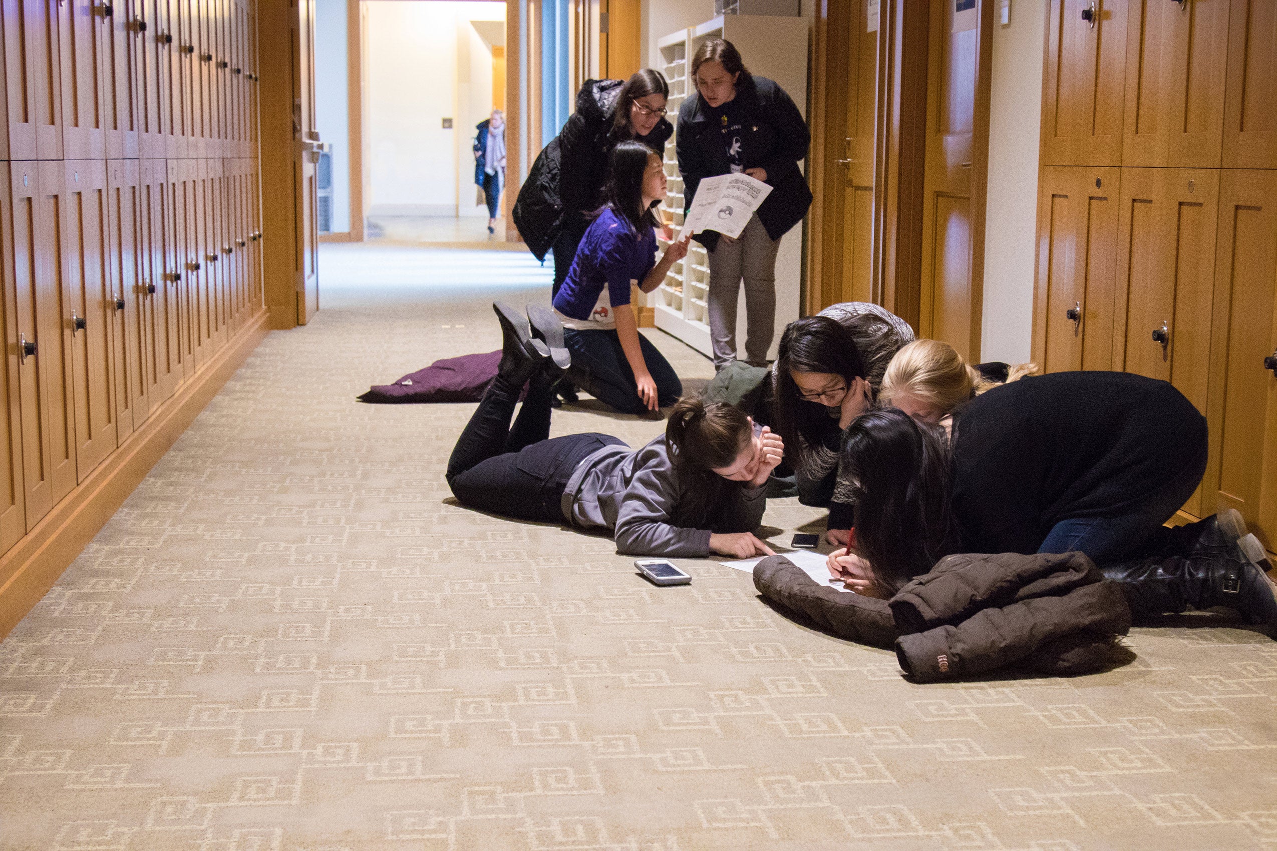 Two groups of students gathered in a hallway, collaborating and discussing