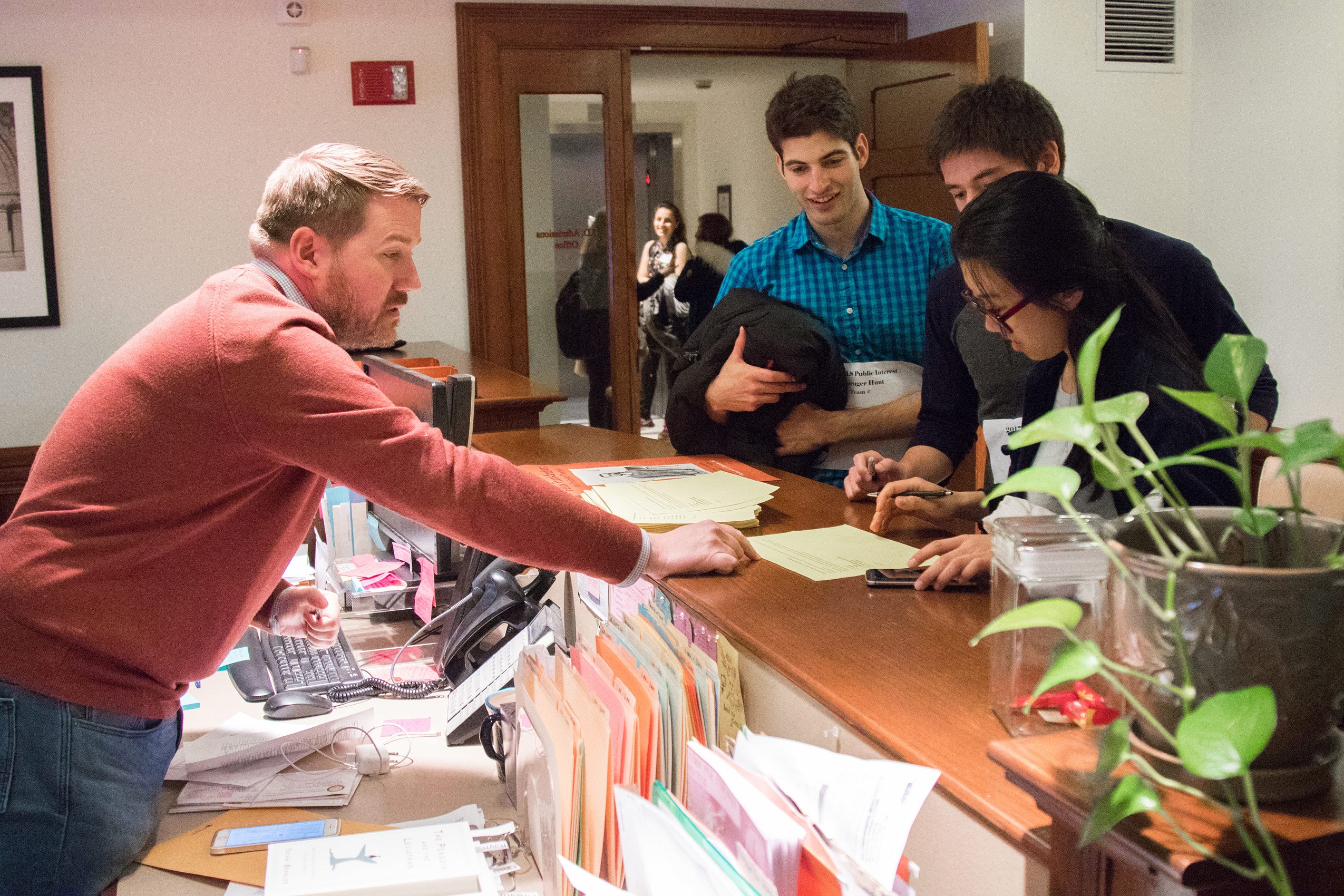 A man pointing at a sheet of paper, held by three students