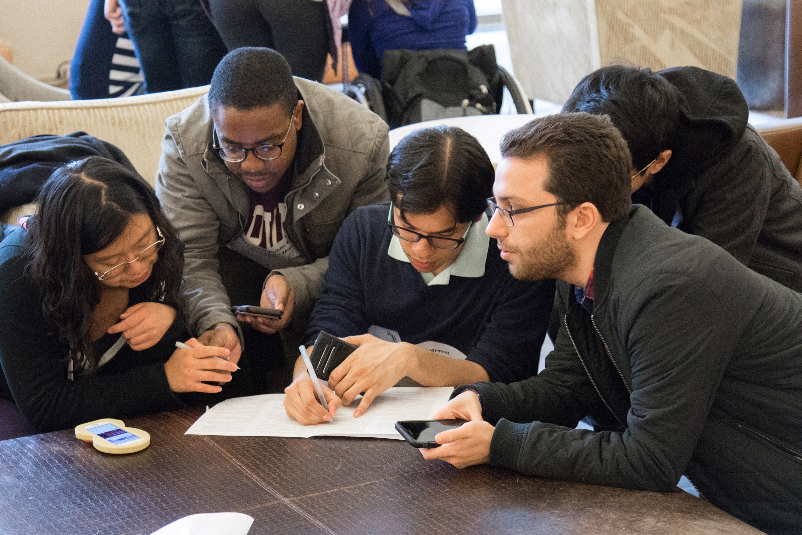 Three men and a woman collaborating over a notebook