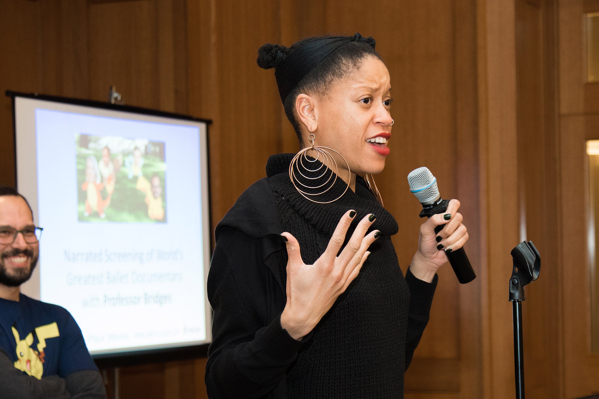 A woman holding a microphone, speaking