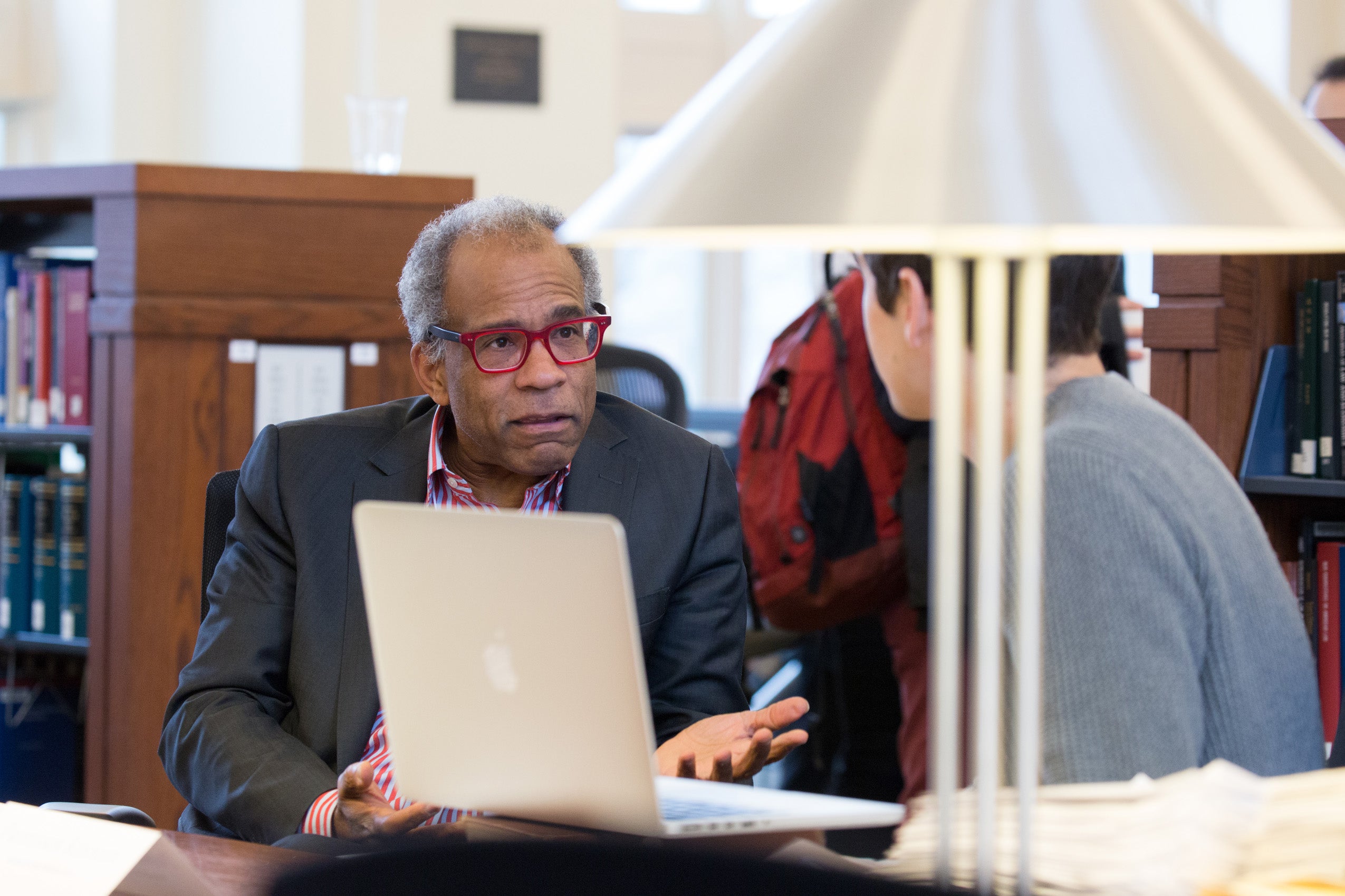 Two men sitting at a table in front of a laptop having a conversation