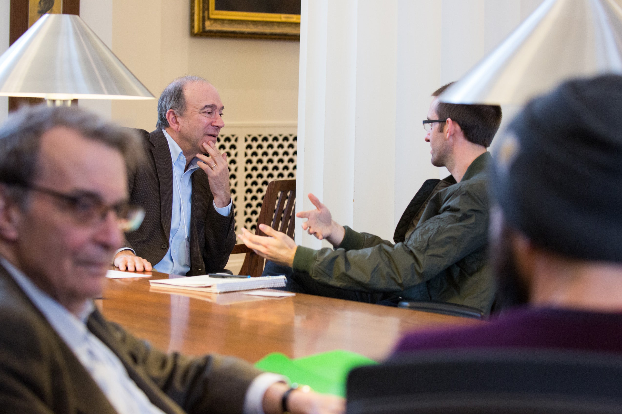 Two pairs of two men sitting at a table having a conversation