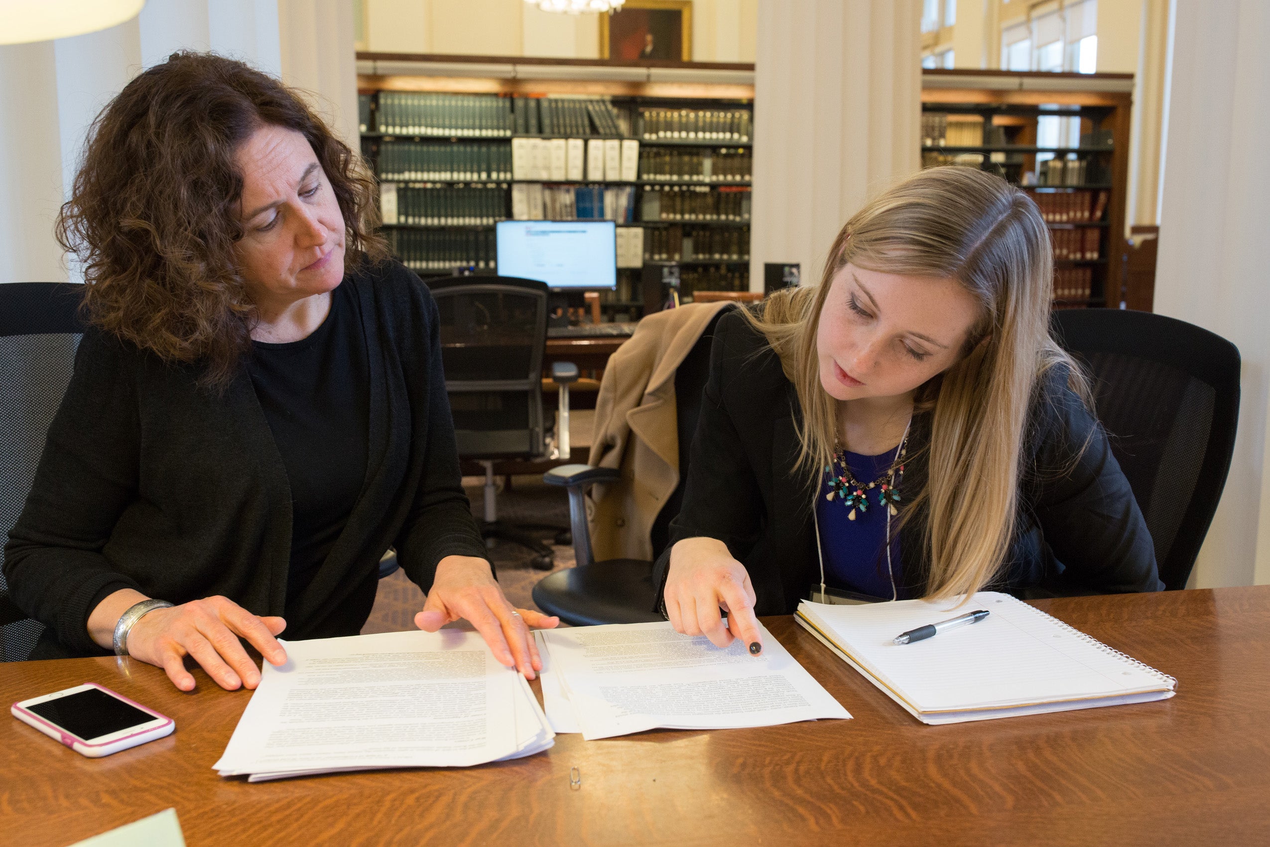 Two women seated at a table looking over papers
