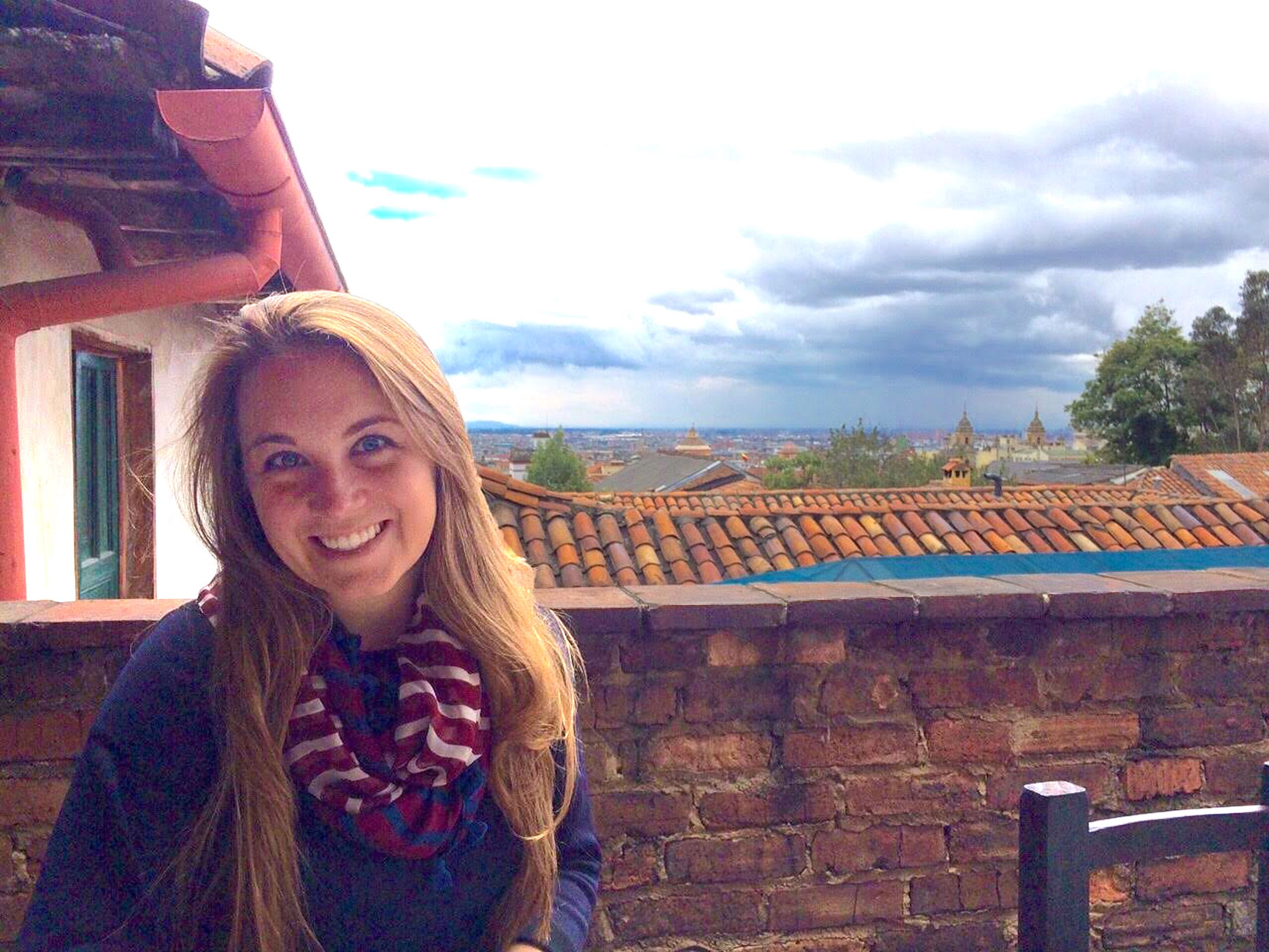 A woman standing on a balcony overlooking a skyline