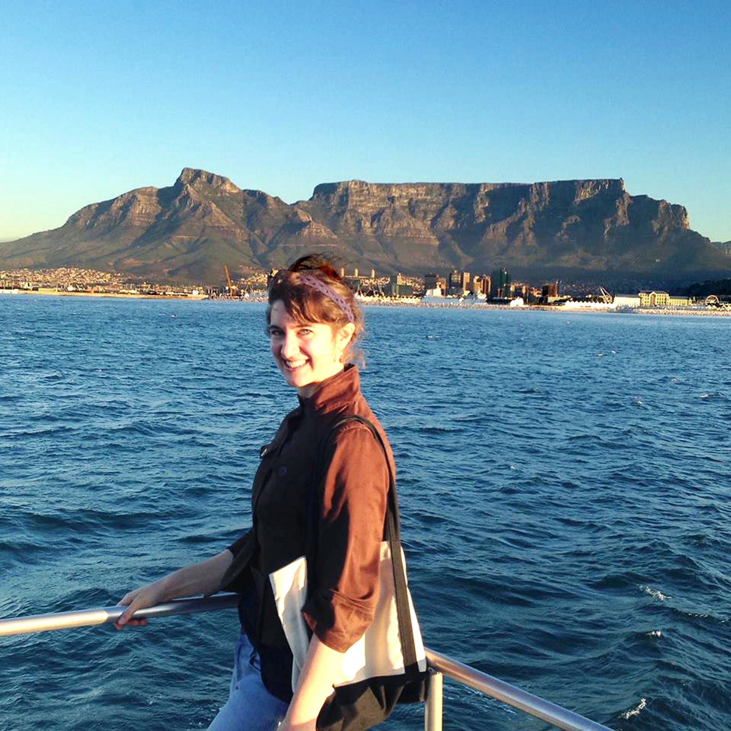 A woman standing and smiling on the bow of a boat