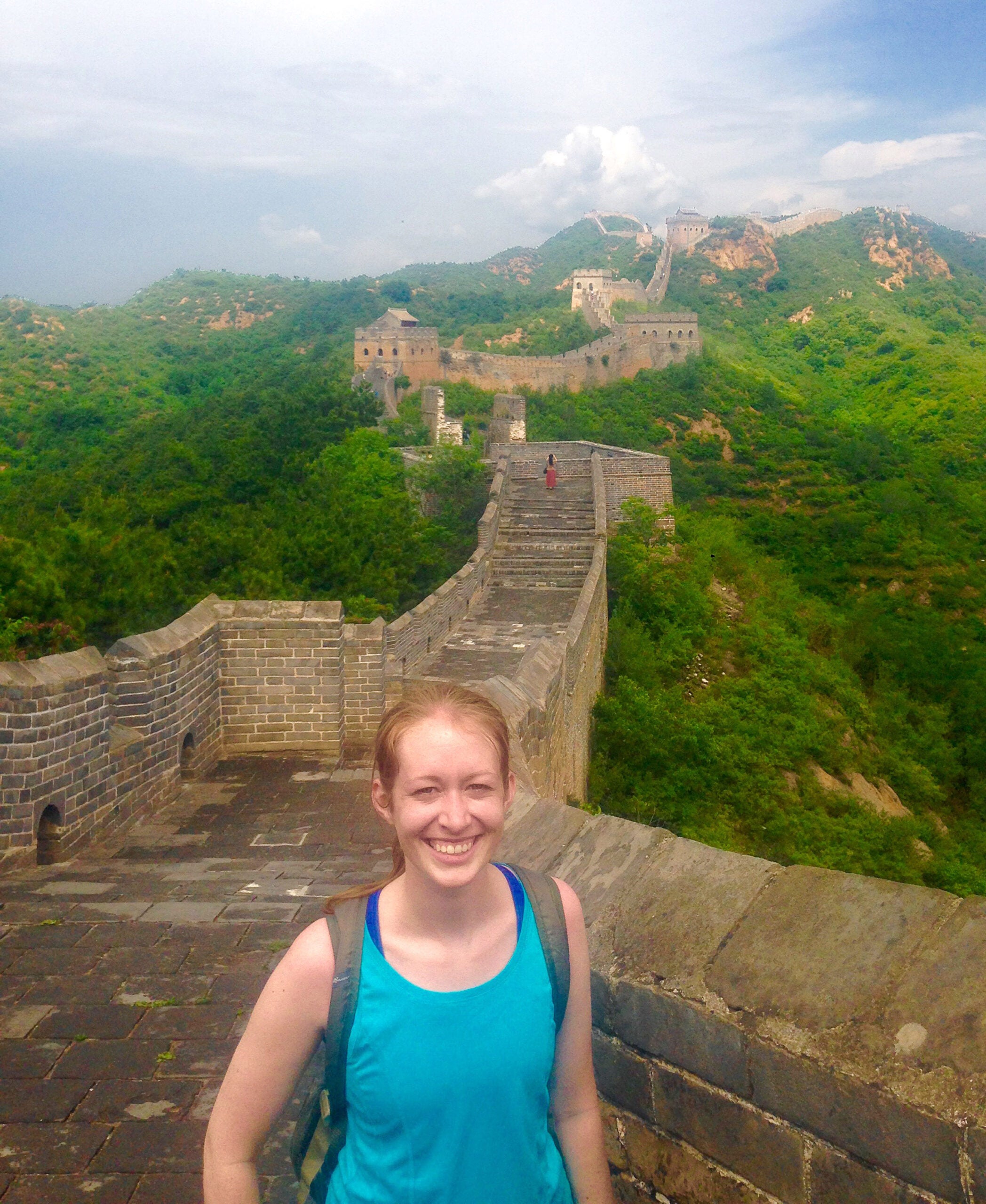 A woman standing and smiling on the Great Wall of China
