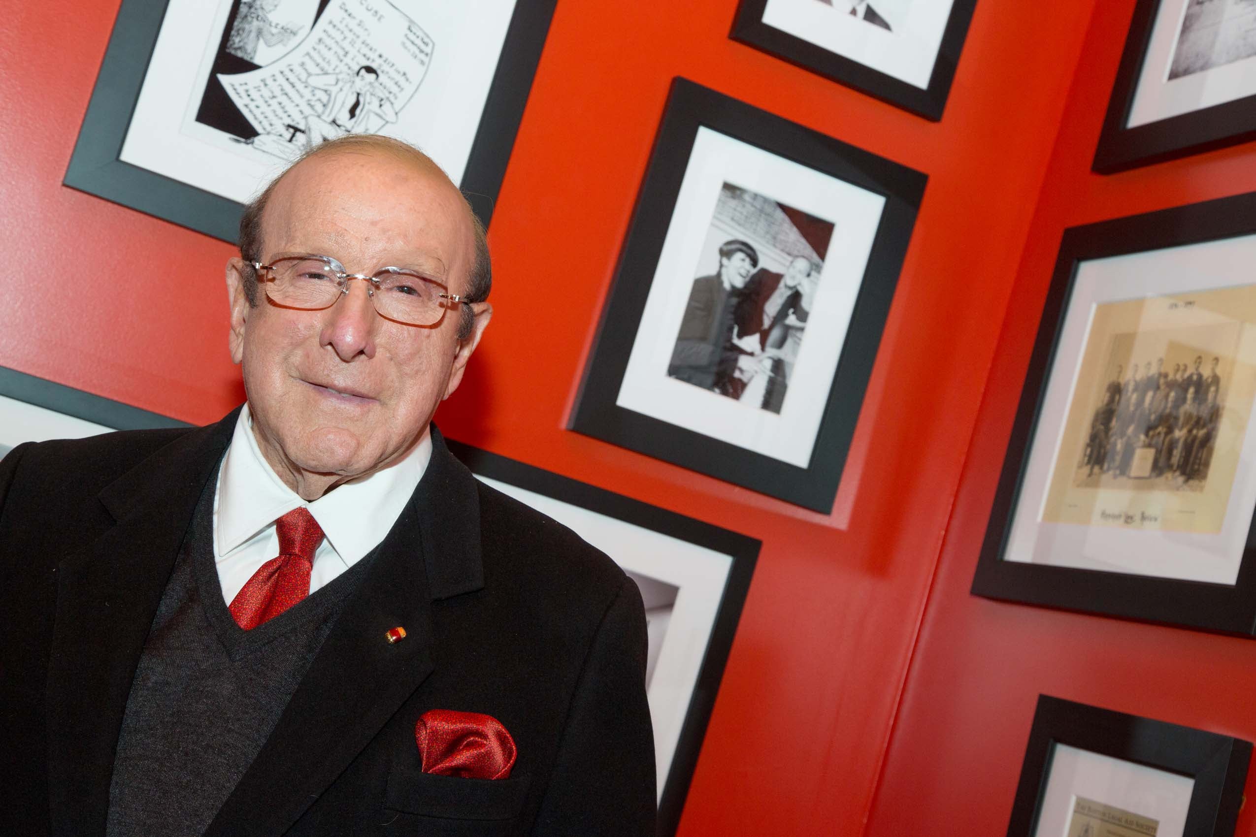 A man posing in front of framed mounted photographs