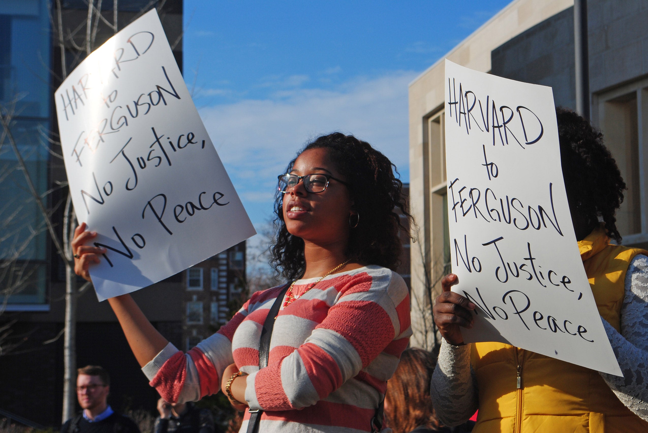 A woman holding a sign that reads 'Harvard to Ferguson No Justice, No Peace'