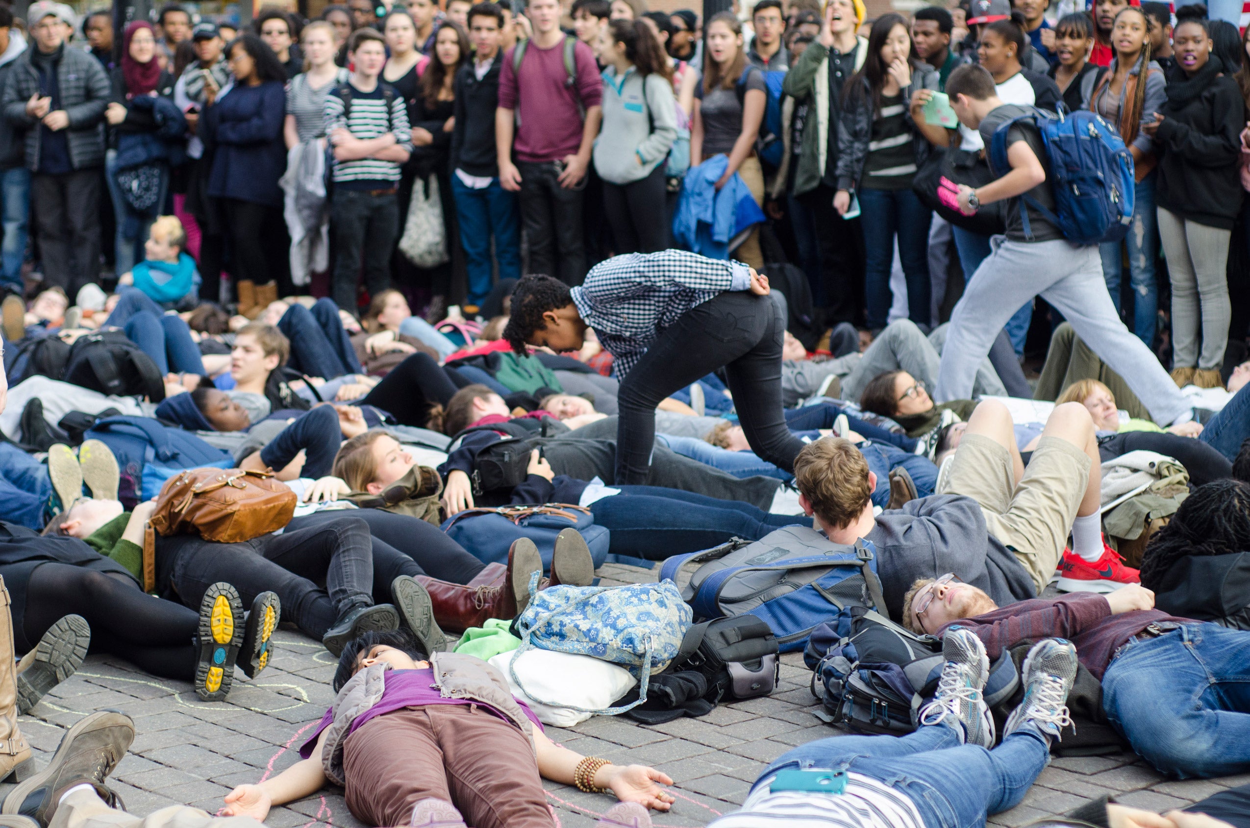 Protestors laying in the street as onlookers watch from the sidewalk
