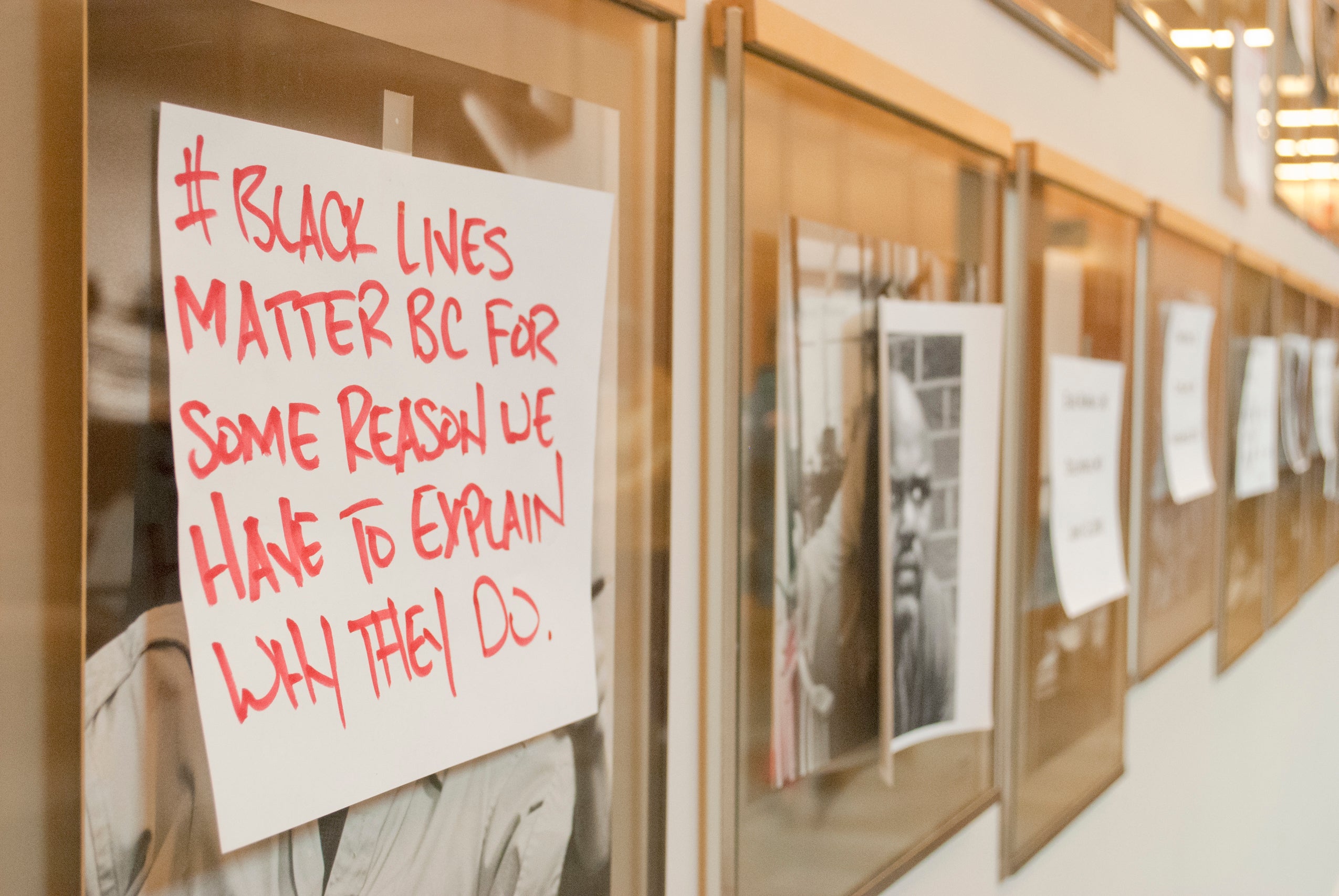 A protest sign put over a framed portrait that reads '#Black Lives Matter bc for some reason we have to explain why they do'