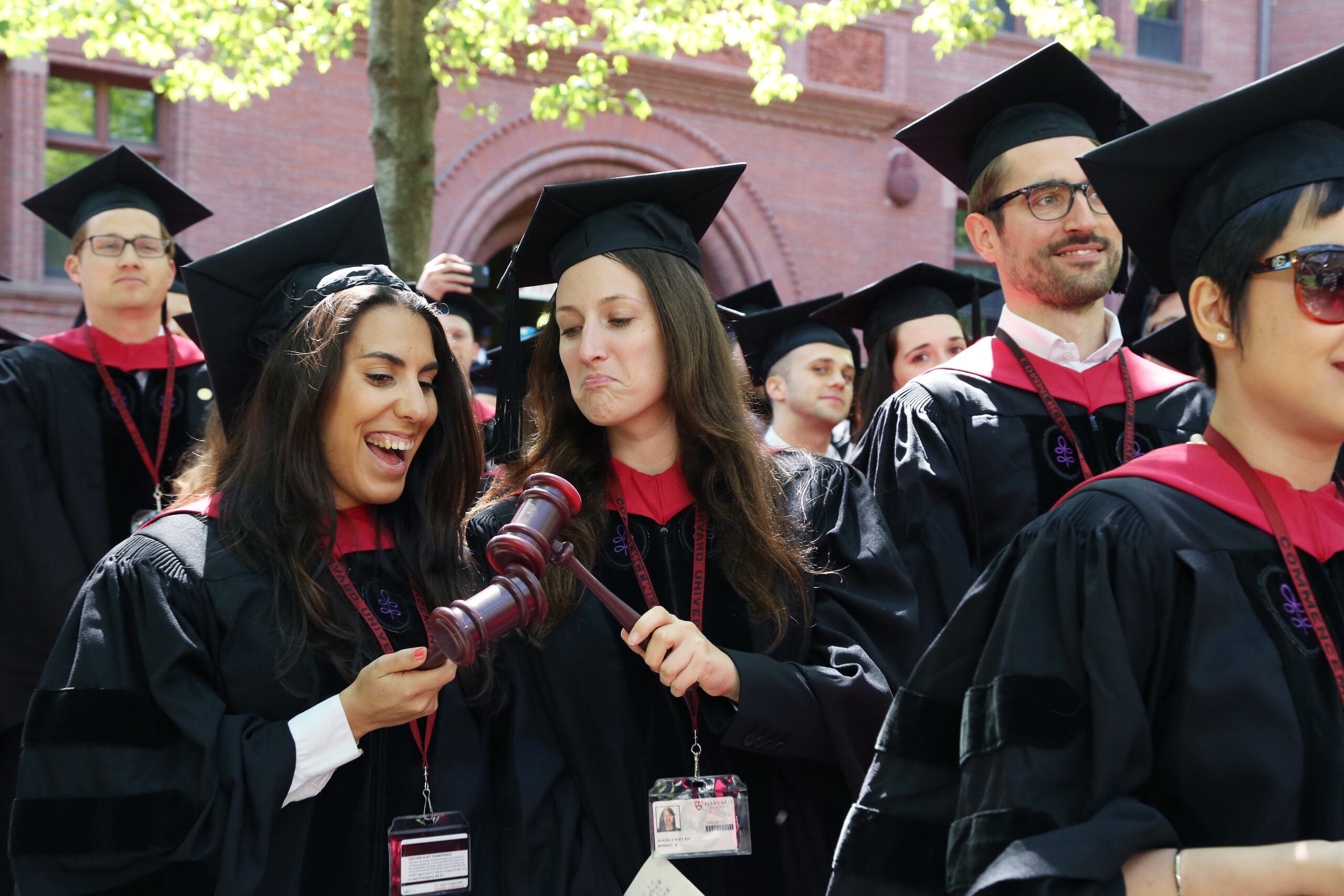 Two graduates in the procession banging plastic gavels together
