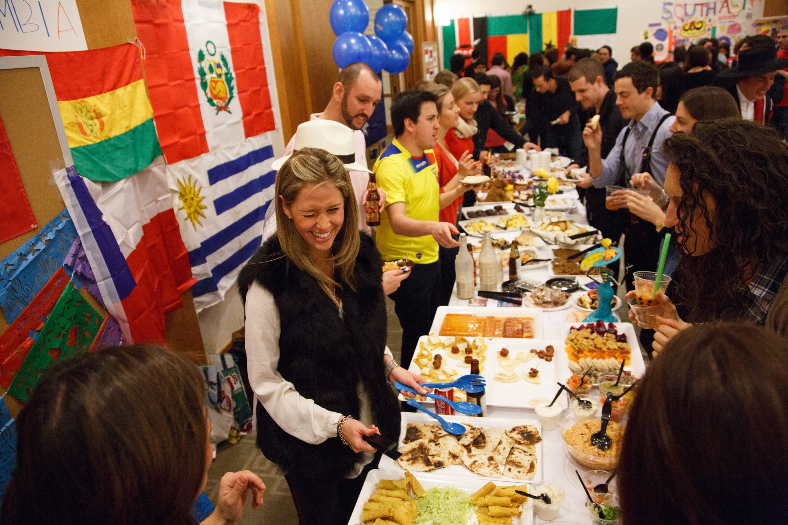 A crowd of people gathering around tables filled with food