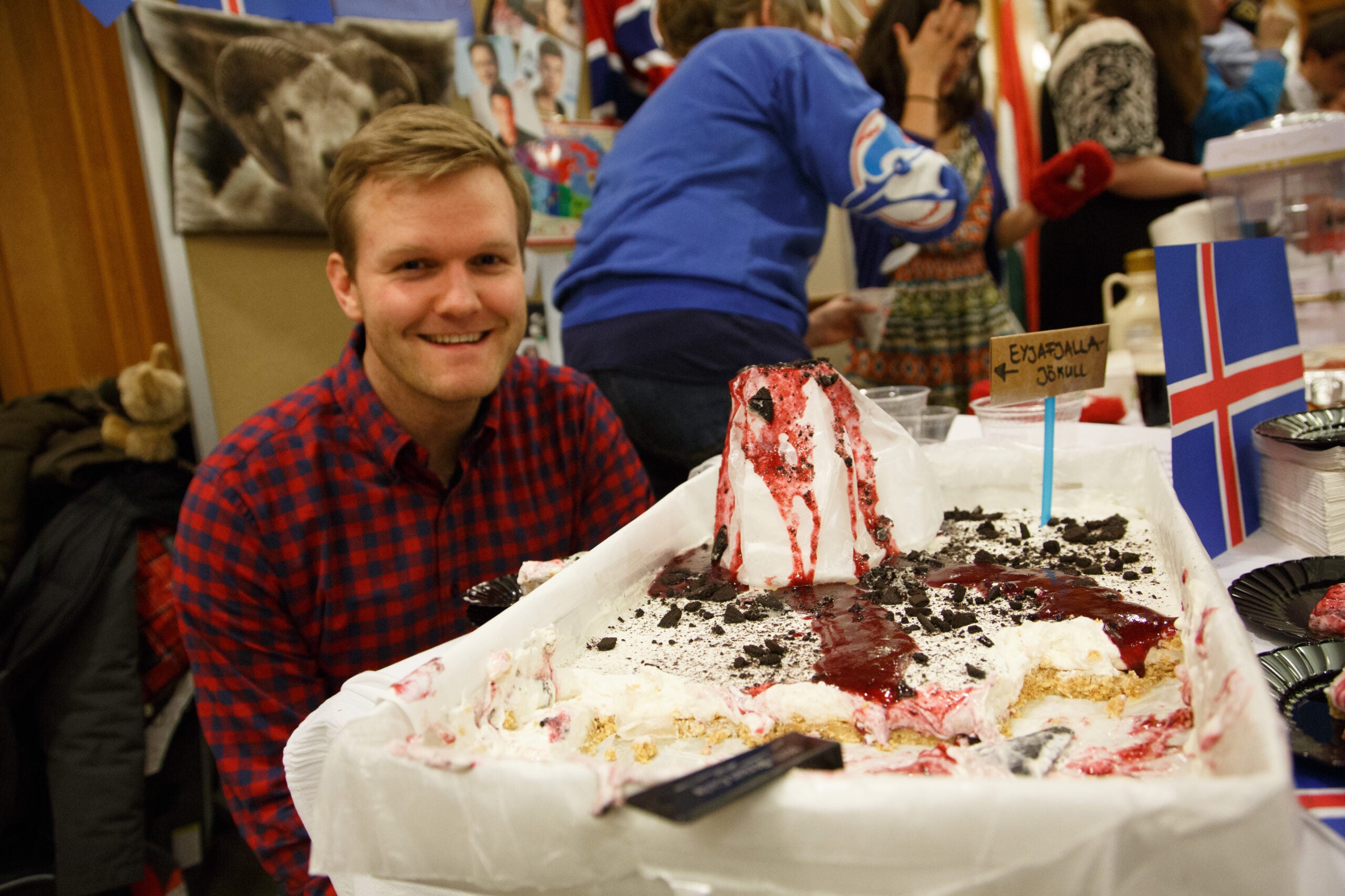 A man siting at a table with a very large cake
