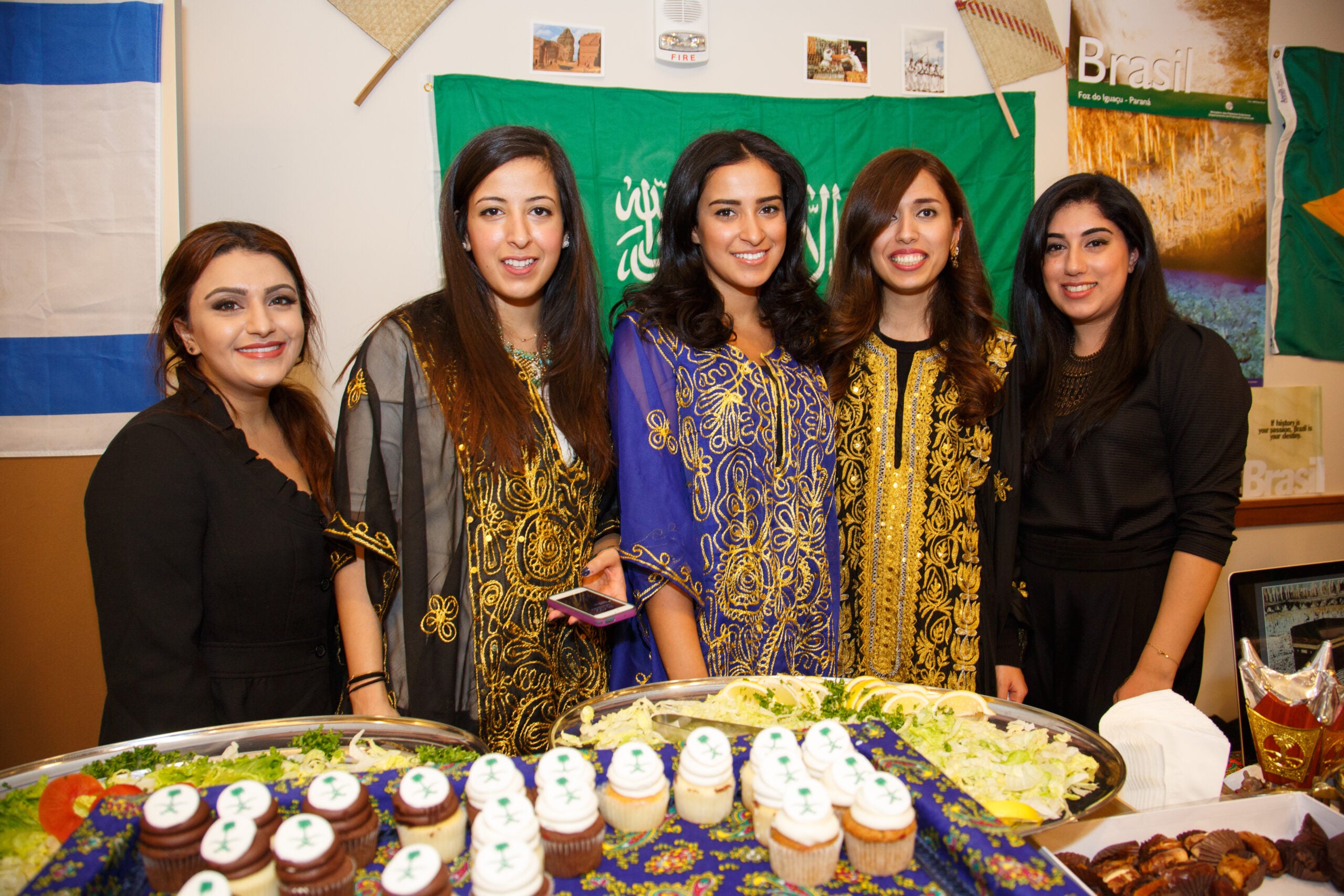 A group of women posing behind a table full of food