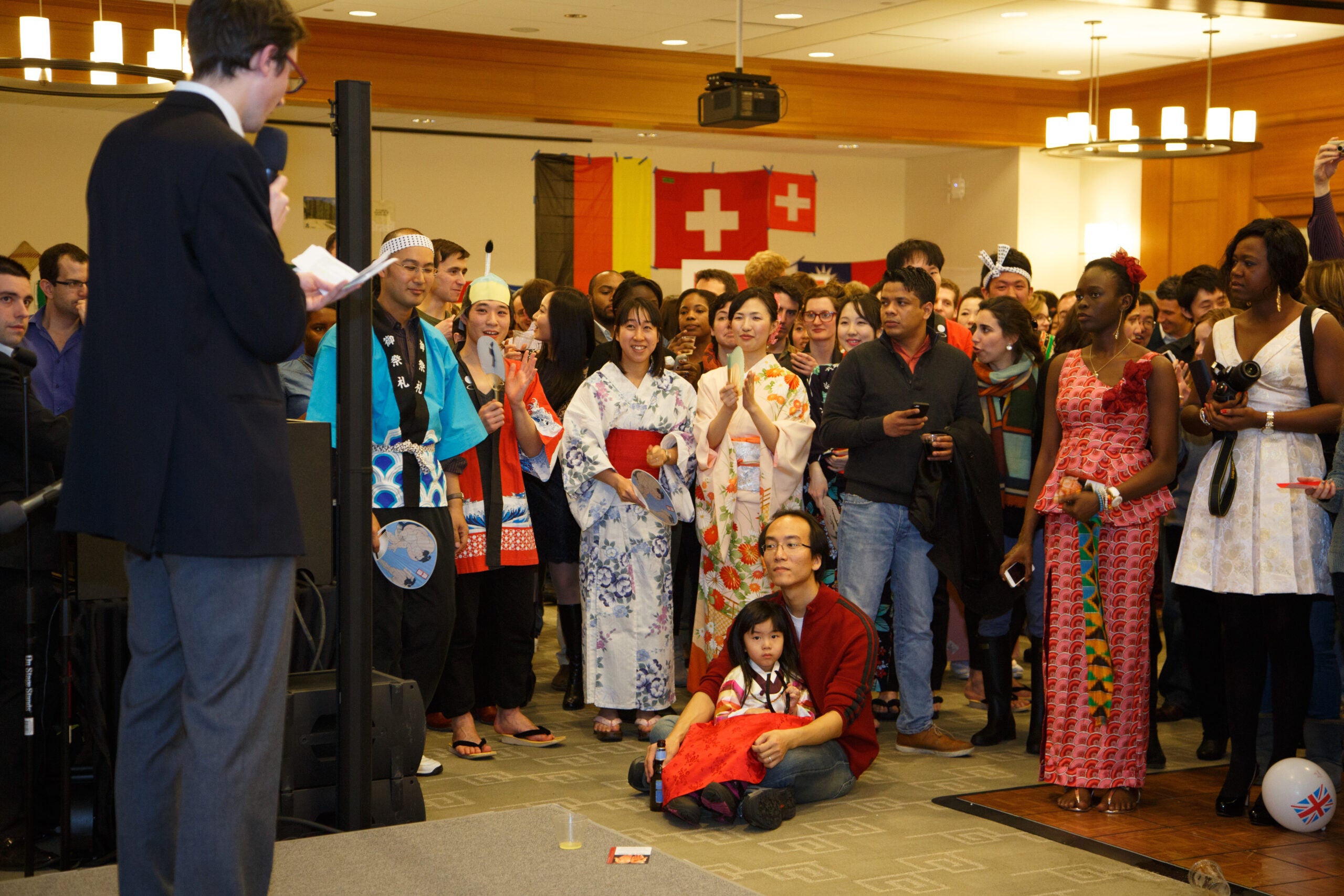 A crowd of people in an audience listening to an emcee speak into a microphone