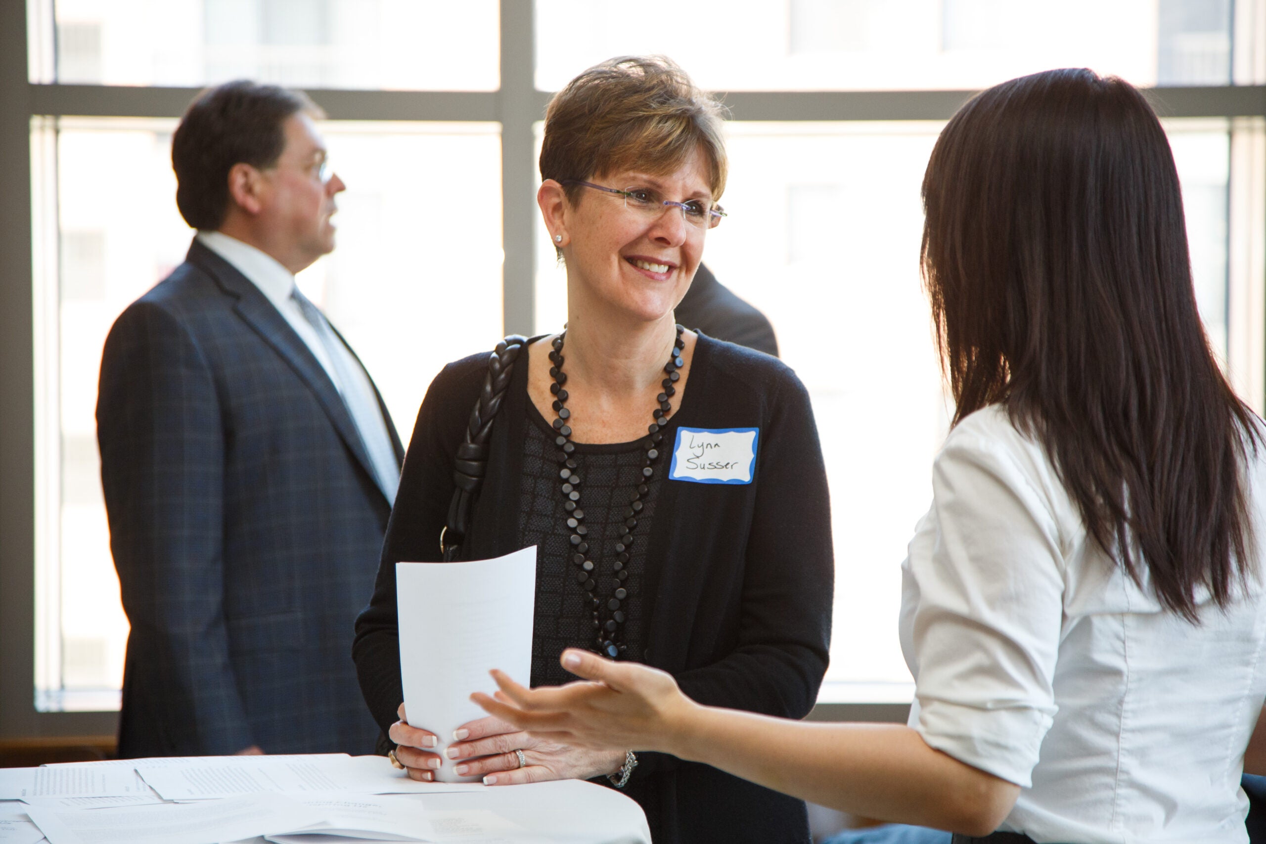 Two women standing at a table having a conversation
