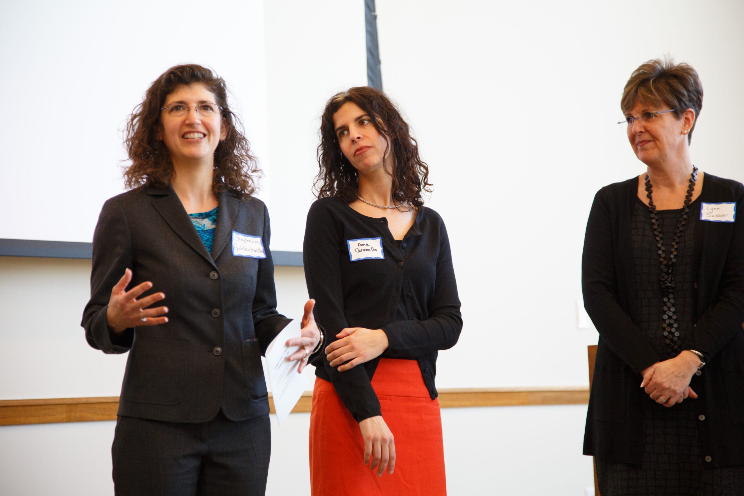Three women standing together at the front of a room