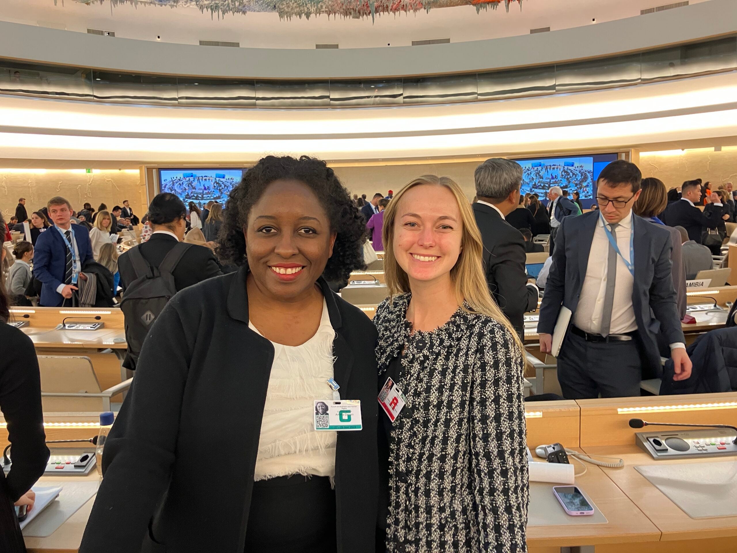 two women smile in a crowded room a the UN