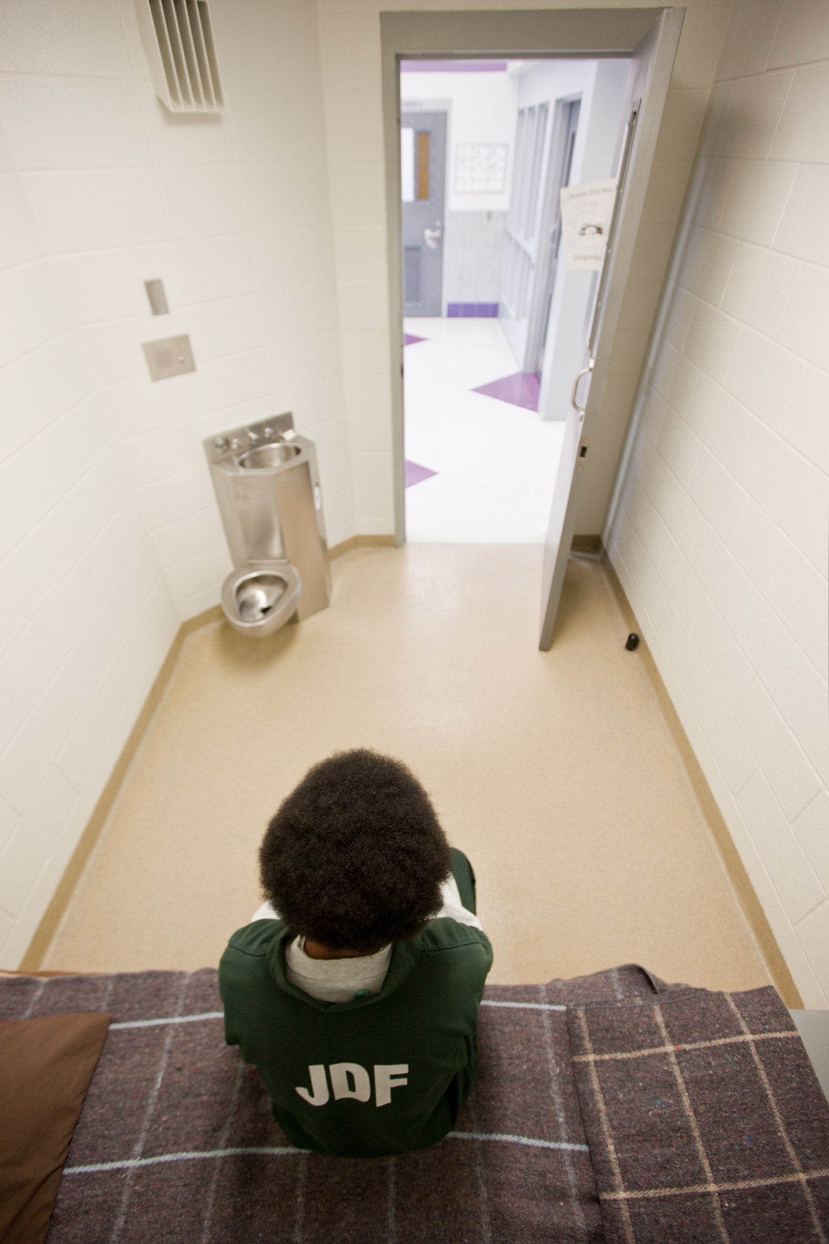 A child sitting in a prison cell