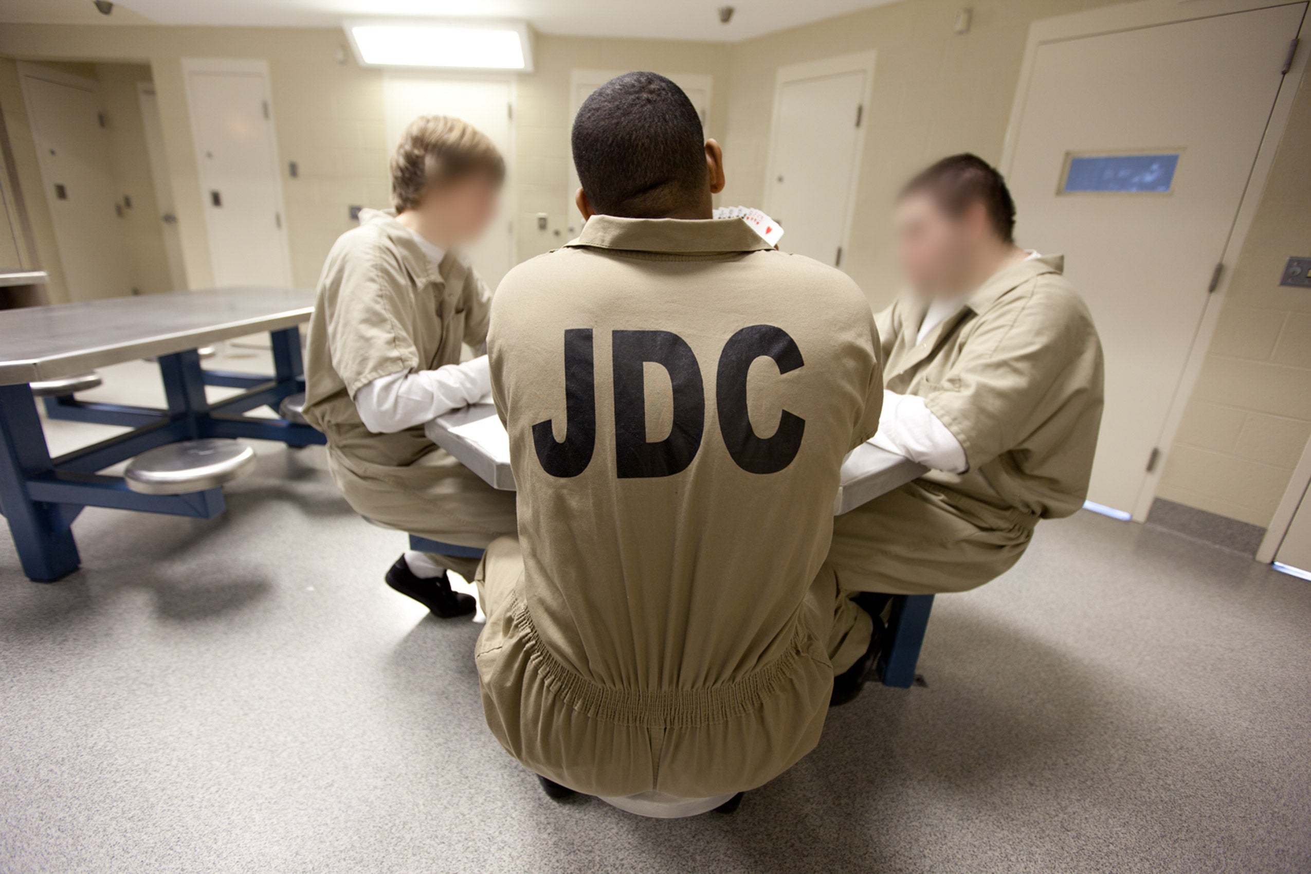 Three young men sitting at a table in a prison