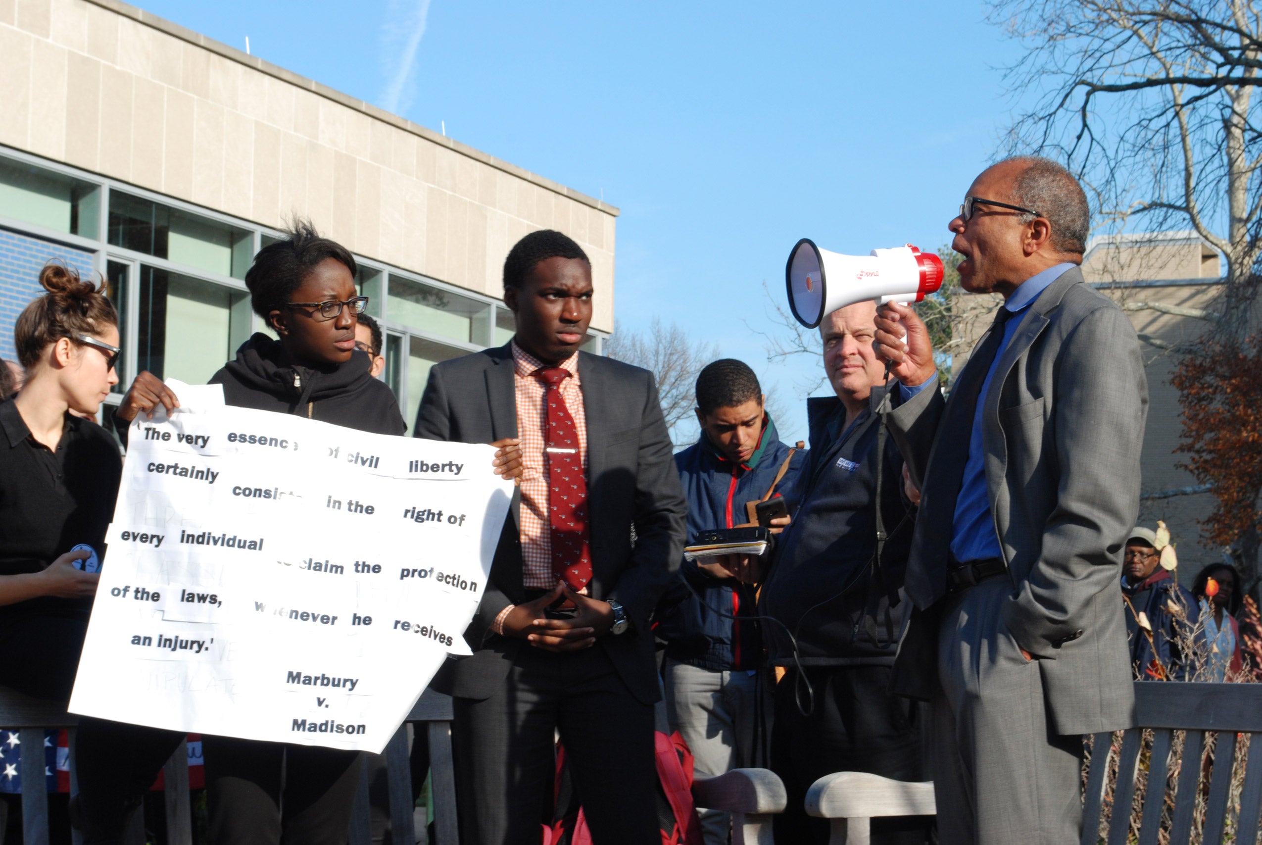 A man speaking into a megaphone in front of a crowd