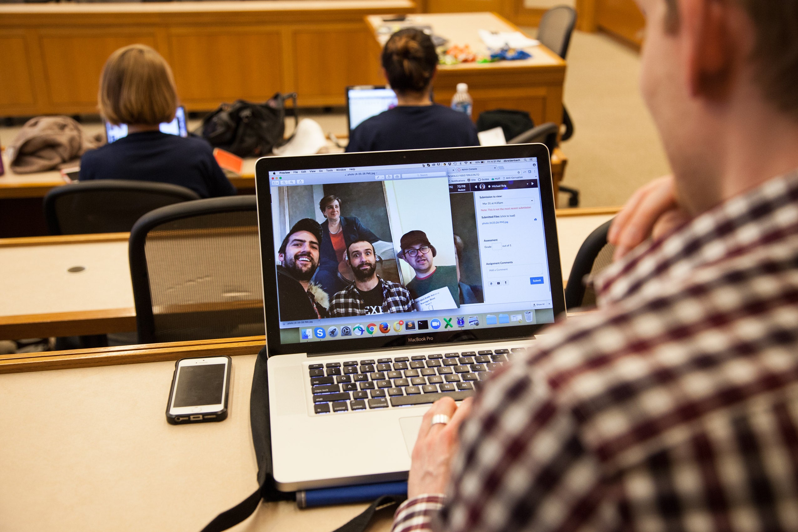 A man looking at a photo of a group of people on his laptop