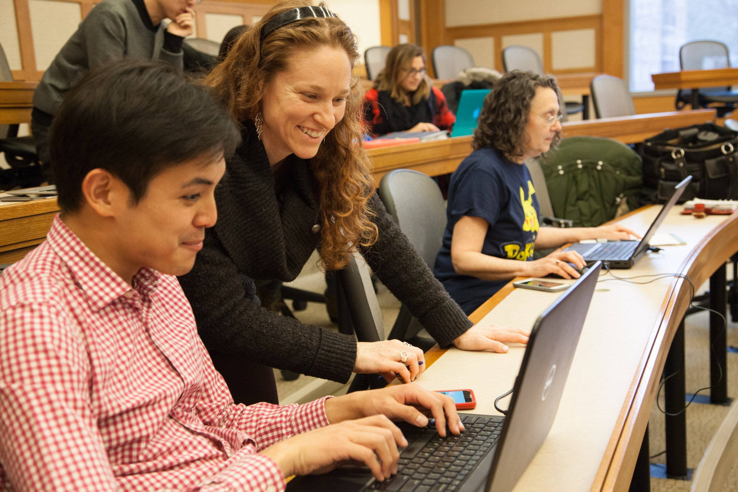 A woman and a man looking at a laptop and smiling