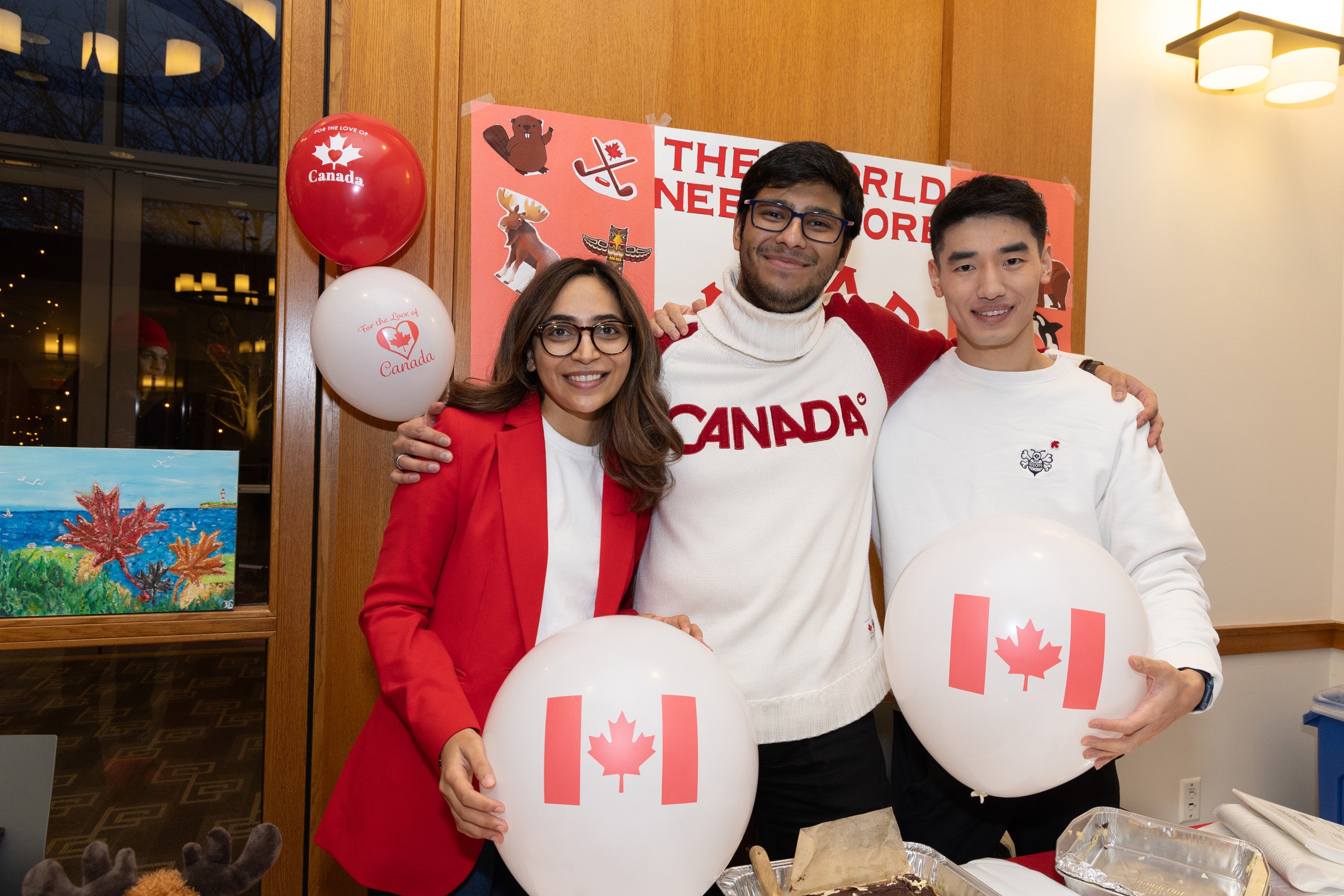 Three students posing holding balloons showing a Canadian flag.