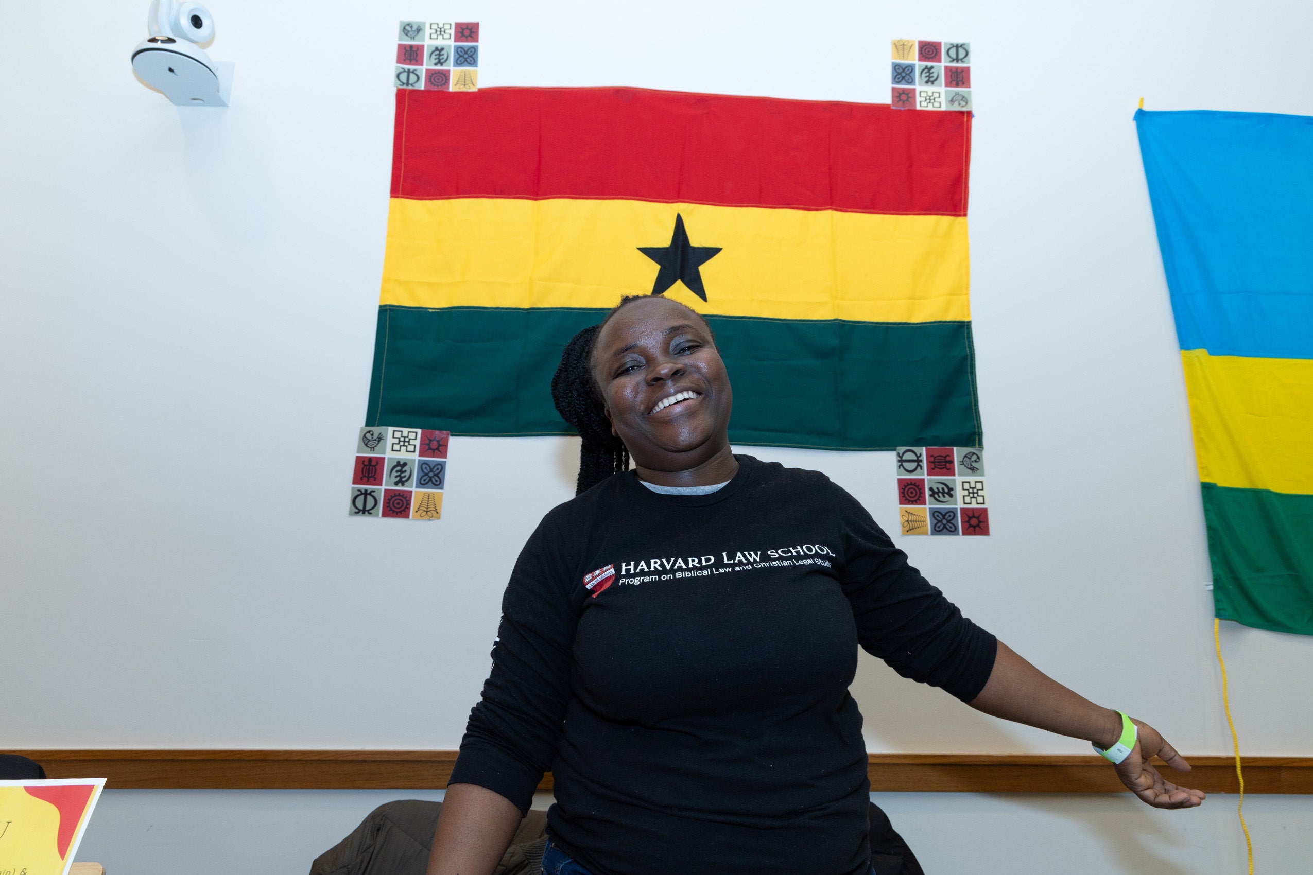 A woman stands in front of a red, yellow, and green flag.at an event