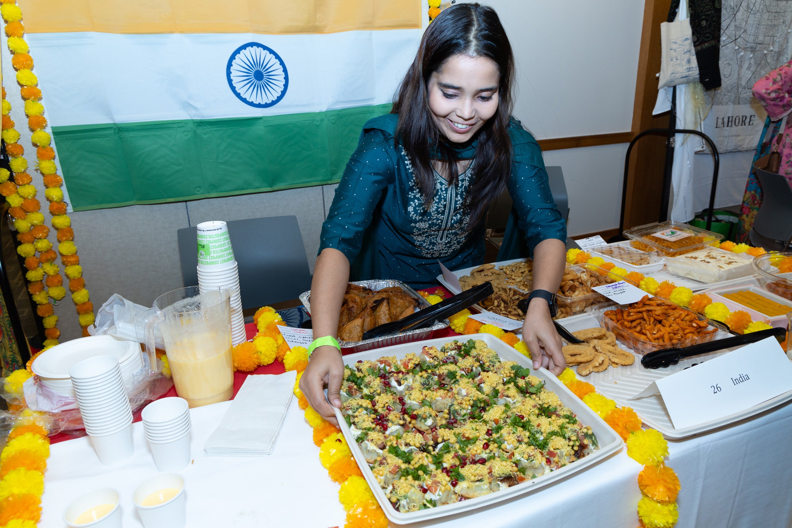 A women standing behind a table displaying food from India.