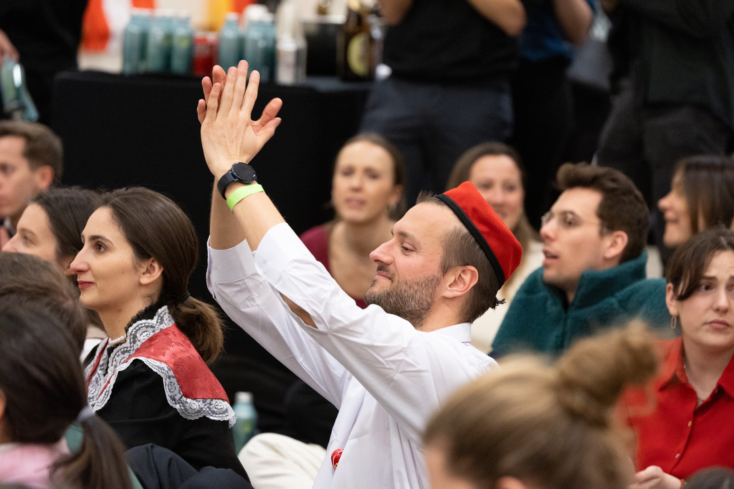 A man sitting on the floor of an event with others claps