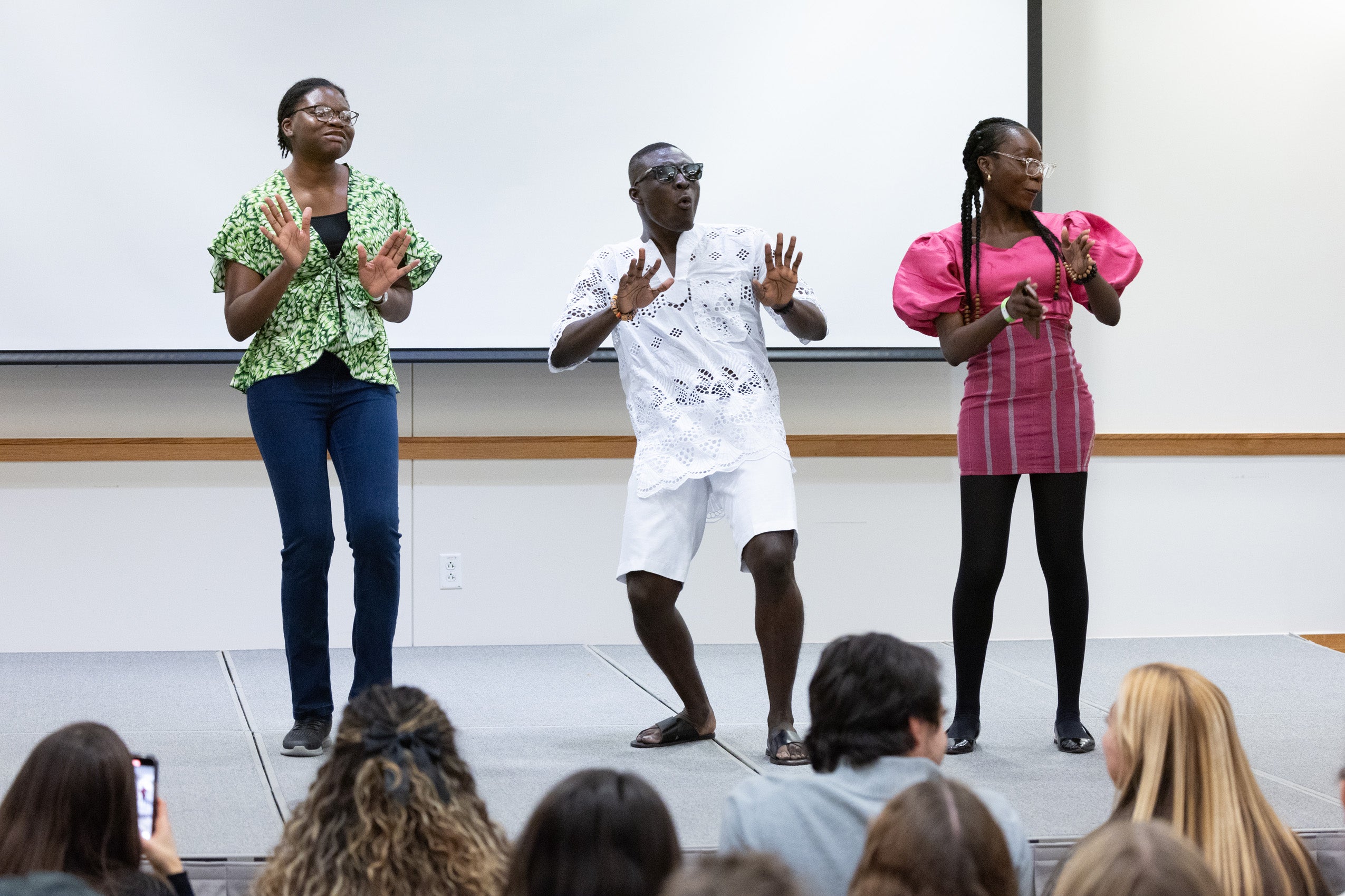 Three students perform on a stage.