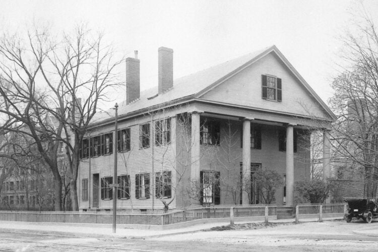 A white house with shutter and tall white columns and a car parked in front.