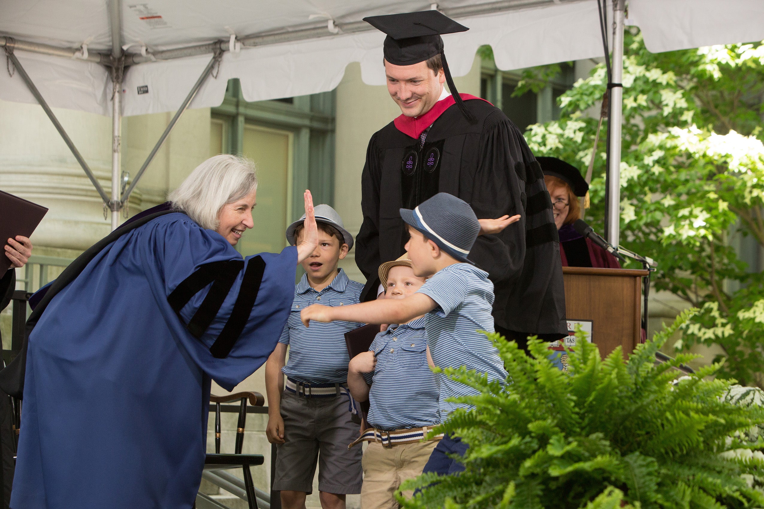 Minow high-fives child on stage during Commencement