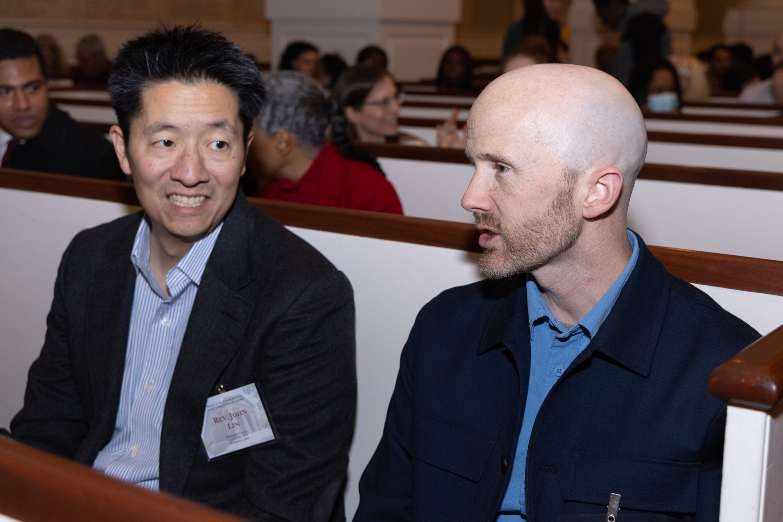 Two men talking in a pew