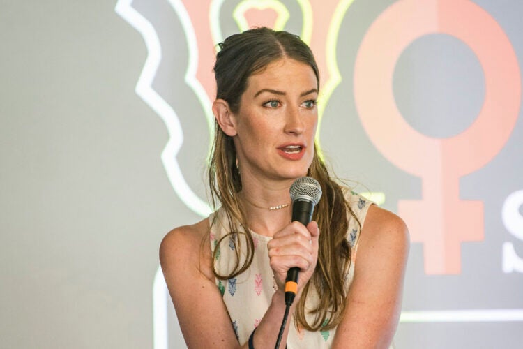Portrait of woman speaking into a microphone at the front of a crowd